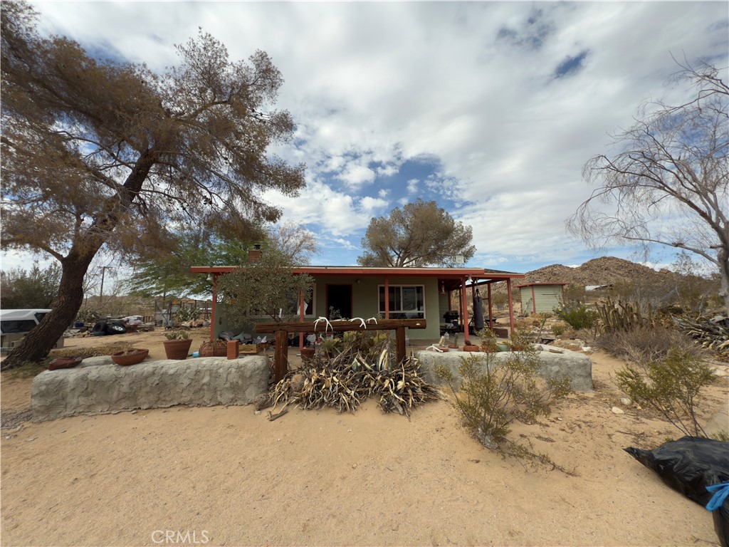 Welcome to your next desert opportunity in Joshua Tree’s sought-after Monument Manor, just minutes from the National Park entrance. This 2-bed, 2-bath home sits on 2.5 acres filled with mature trees, covered porches, and wide-open views. Inside you’ll find plentiful windows, an original brick fireplace, an office area, plus a large storage building, screened garden, and a vintage trailer. With public water, mini-split heating/AC, and a fully fenced lot, all the essentials are already in place; add light updates to unlock major upside and transform this into the perfect retreat or income property.