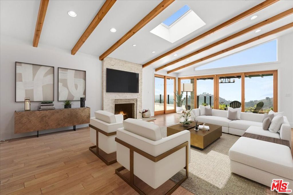 Behind a private gate, in one of Brentwood's most coveted communities, lies a striking, single-story Contemporary estate with commanding jetliner views stretching from canyon ridges to the shimmering Pacific Ocean. This meticulously restored residence blends architectural elegance with modern luxury, offering the utmost privacy and serenity. A grand motor court makes an impressive arrival statement, leading to a stately center hall and an expansive formal living room with a sculptural stone fireplace all framed by panoramic vistas. The formal dining room sets the stage for refined entertaining, while the chef's kitchen is outfitted with top-tier appliances, bespoke cabinetry, and an inviting breakfast nook. The primary suite is a sanctuary of light and space, with floor-to-ceiling glass that captures breathtaking views and a spa-inspired dual bathroom finished in white granite with stone tile shower and soaking tub. Rich hardwood floors flow throughout, while multiple outdoor patios provide the perfect backdrop for al fresco dining, fireside lounging, and unforgettable sunset gatherings by the firepit. An extraordinary offering for those seeking design, privacy, and views without compromise.