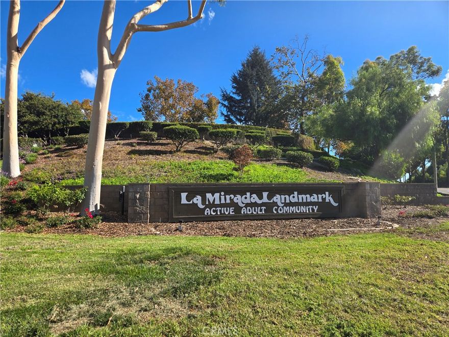 Welcome to this stunning, move-in-ready 2-bedroom, 2-bathroom senior condo located in an Active Adult Landmark Community exclusive 55+ guard-gated neighborhood offering 24/7 security and resort-style amenities. Step inside to an open-concept floor plan filled with natural light from multiple skylights and new recessed lighting throughout. The spacious living and dining areas flow seamlessly into the beautifully updated kitchen, featuring granite countertops, cabinets with convenient pull-out drawers, and an elegant ceiling light tray. This freshly painted home boasts crown moldings and rich wood-pressed flooring throughout. The primary bedroom includes a large walk-in closet and an en-suite upgraded stone-tiled bathroom. The second bedroom offers a generous closet, new window covering, and easy access to the second bathroom, which features a modern walk-in shower in the hallway. Enjoy the convenience of a dedicated laundry closet on the balcony with a stacked washer and dryer, as well as a detached garage and plenty of guest parking nearby. A brand-new refrigerator is also included. Community Amenities: Clubhouse, Swimming Pool & Spa, Tennis Courts, Exercise Room, Library, Scenic Walking Paths. Ideally located near La Mirada Golf Course, Ralph B. Clark Regional Park, shopping centers, restaurants, major markets, and entertainment. Easy access to the 5 and 91 freeways. Don't miss this opportunity to live in a senior community that combines comfort, convenience, and an active lifestyle!