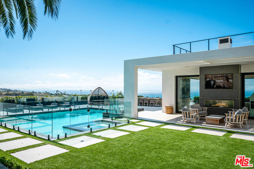 Perched above the Pacific with sweeping ocean views, this modern Malibu Park coastal estate offers a rare blend of architectural sophistication, resort-caliber amenities, and unparalleled privacy designed for effortless entertaining and inspired coastal living, from sunrise swims to sunset soirees. Behind secure gates, a dramatic motor court framed by mature trees and serene ponds sets the tone for this chic, sun-drenched sanctuary. Step inside to a vaulted entry with a floating staircase, gallery-like walls, and floor-to-ceiling glass that dissolves the boundary between indoors and out. The expansive great room flows seamlessly into the chef's kitchen, an entertainer's dream opening to a sun-soaked terrace with a sparkling pool, spa, fire pit lounge, and full outdoor kitchen. Every inch of the landscaped grounds is thoughtfully curated, from the lush fruit orchard to the organic vegetable garden, offering a true farm-to-table lifestyle in the heart of Malibu. Designed for both work and play, the home features a private ocean-view office, a custom-built cinema, an ocean-facing fitness studio, and a flexible lower-level suite. The primary bedroom is a masterclass in coastal luxury, with two private terraces and a spa-inspired bath anchored by a statement-making brass soaking tub by VAST. Sustainable drought-conscious landscaping, a whole-home water filtration system, and newly installed solar complement the property's effortless elegance. Move-in ready and moments from the beach, this estate is more than a home; it's an invitation to live the Malibu dream in its most refined form.