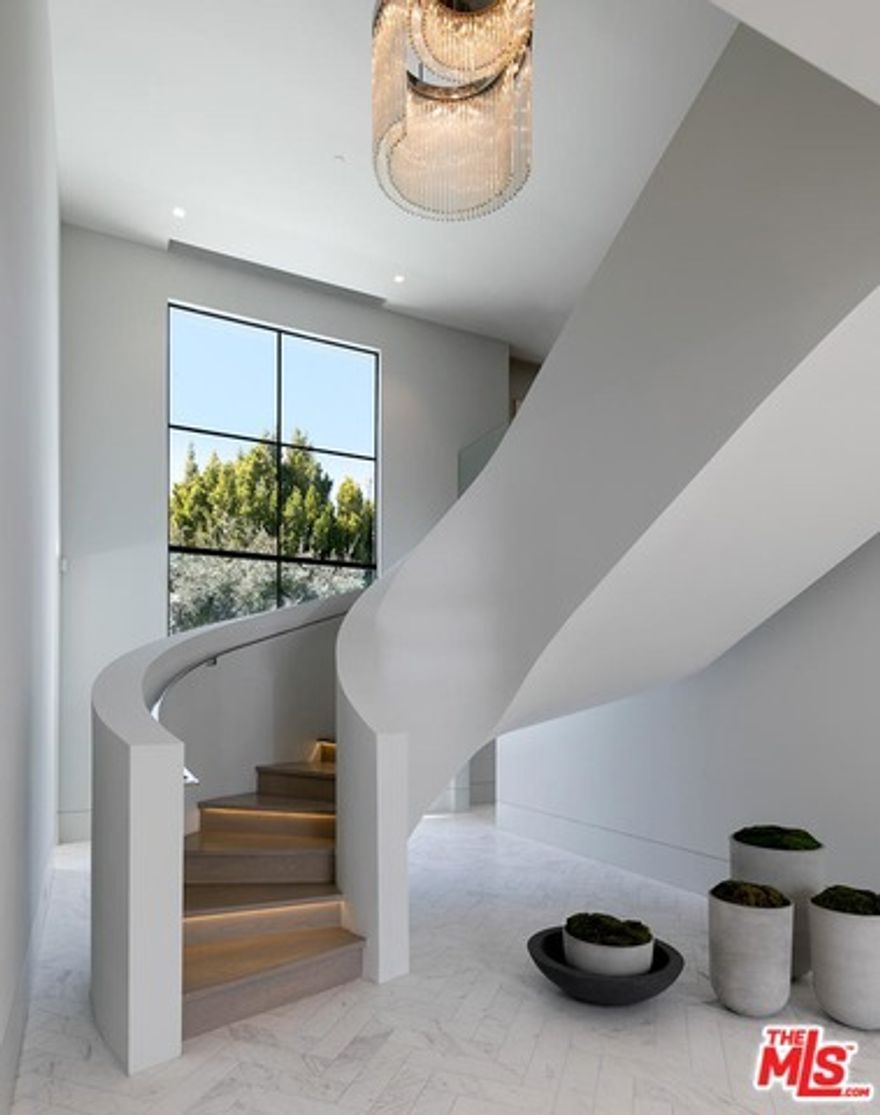This extraordinary European estate in prime Beverly Hills showcases grand-scale living spaces, magnificent grounds and iconic views of L.A. Country Club and Century City in a serene and private setting. Behind gates on almost an acre of flat land, a grand, wraparound motor court studded with olive trees leads to sweeping, light-infused living spaces, including a living room with restaurant-caliber bar, dining room, theatre, auto gallery, phenomenal chef's kitchen and great room lined with French doors to impeccable grounds. A striking sculptural staircase leads to an open living area, office and six ensuite bedrooms, including the exceptional master with dual bathroom wings and showroom closets. A separate guest house and magnificent grounds, including a floating infinity pool and spa, water and fire features, cabana, outdoor kitchen, expansive lawns, and old-world gardens complete this unprecedented offering, just a heartbeat from the renowned shops and restaurants of Beverly Hills.