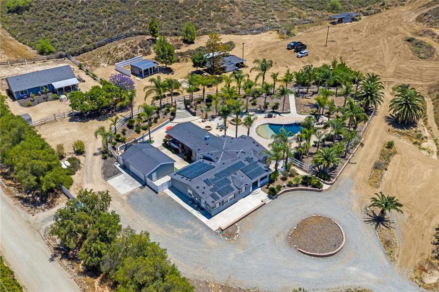 Hidden Temecula Compound For Sale

3 Separate Homes 7 Bedrooms, 6 Bathrooms, Pool & Spa, Nearly 5 Acres, Solar-Powered, Income-Producing! Welcome to your private paradise in the heart of wine country! Nestled on nearly 5 secluded acres, this incredible Temecula compound offers three separate residences, making it ideal for multi-generational living, rental income, or an expansive retreat. This income-producing property is loaded with opportunities & charm, from its modern remodels to its resort-style backyard. MAIN RESIDENE - Fully remodeled & designed with a modern farmhouse aesthetic, the main home features 4 Bedrooms, 2 Bathrooms,  2-Car Garage with 220V Electrical. Open-concept layout with natural light & neutral, designer finishes. Sleek kitchen with custom cabinets, high-end appliances, self-closing drawers, & elegant quartz counters. Spacious laundry/mudroom for added convenience. Luxurious master suite with walk-in closet, retreat/flex space, & direct access to the backyard Stylish bathrooms with walk-in showers, quartz countertops, & contemporary tile. GUEST HOME (Fully Permitted) Fully functional & beautifully finished 1,450 sqft single-story guest home offering: 3 Bedrooms, 2 Bathrooms Open layout with tile floors & a large, well-equipped kitchen. Spacious fenced front porch perfect for relaxing or entertaining. TINYHOME/STUDIO This cozy, versatile 240 sq ft space is perfect for: Guest suite, pool house, home office, gym, or short-term rental. Features a full bathroom, space for a kitchenette, & open concept layout. BACKYARD PARADISE An entertainer’s dream backyard: Massive saltwater pool with a large baja shelf and spa. Covered outdoor kitchen/bar—ideal for hosting and cooking for large gatherings. Fire pit, expansive patio space, and lush landscaping. Detached outdoor bathroom with walk-in shower, dual toilets, washer/dryer hookups. Fruit trees and grapevines: Peach, Plum, Fig, and more! ADDITIONAL FEATURES: 2 Separate Septic Systems (Main home on one; Guest & Tiny Homes on the other). Solar-powered for energy efficiency. Multiple garages: Main Home: 2-Car with 220V (great for welding or EV charging) Additional Garage 1-Car with 220V, RV hookups, and water access. Conveniently located near Temecula’s top wineries, schools, shopping, & dining. Experience upgraded country living with total privacy and endless possibilities! Whether you’re looking to invest, host, relax, or grow, this multi-home Temecula estate is the one you’ve been waiting for!