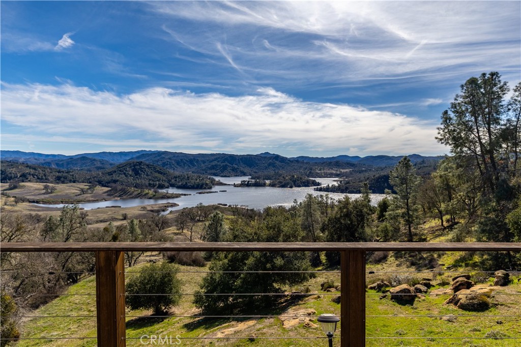 Tranquil Mountain top retreat with million-dollar views of Santa Margarita Lake! Custom built home with exceptional features of an impressive rock centerpiece that greets you as you enter which is equipped with a waterfall and koi pond. The rock continues into a daunting chimney for both the living room and the family room fireplaces, one with a wood burning stove inserts for functionality and beauty. The massive beamed ceilings are finished with tongue and groove wood providing ample space for art or collections. The open floor plan includes a dining area suitable for sizeable gatherings. The kitchen is a chef's dream with a huge butcher block island, built in refrigerator and freezer, double ovens, lots of storage and counter-space plus a massive walk-in pantry/butlers pantry. The tinned center ceiling provides a modern expression. The attached breakfast nook has a spectacular view of the lake.
The primary suite has it's own wing with incredible views of the lake both inside and off it's deck. The on-suite bath is spacious with separate vanities, soaking tub, and shower. The suite is equipped with two wardrobe closets and a walk-in closet...no need to worry about a place for your belongings! Another main-level bedroom is in the west wing with a 3/4 bathroom. Downstairs are two more rooms and one bathroom with a shower. The indoor laundry room is furnished with a washer, dryer, sink, hidden ironing board, and built-in storage. The frontage acreage is sometimes used for cattle or horses and is cross-fenced. Nearby is the workshop with a concrete floor and a Dunn barn with a concrete floor that was once used for housing. The ideal mixture of usable land and a mountain top home!