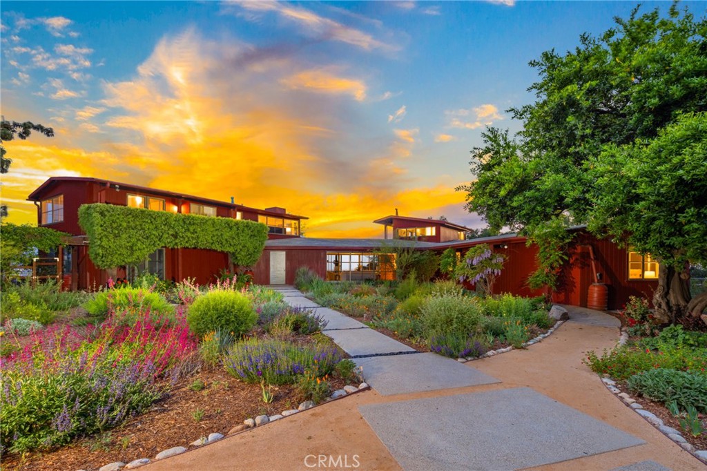 Views to Everywhere! Welcome to the architecturally significant “Willis House” built in 1941 and designed by renowned architect William Wilson Wurster. The house is an ideal example of indoor/outdoor Mid-Century Modern living. It has been remodeled and updated yet retains many of the original details. The house boasts 3,986 square feet of living space, an acre lot, five bedrooms and five bathrooms. The first level features a living room with a high-beamed ceiling, gleaming concrete floors and floor-to-ceiling sliding window walls that open to the beautiful valley and mountain vistas in front and back. The remodeled kitchen has abundant cabinets and storage, quartzite countertops, lit display cabinets, Blue Star stove, stainless steel appliances, separate eating area, breakfast bar and a walk-in pantry—the eating area has floor-to-ceiling window walls to welcome the outside in. The cozy den has pocket doors, a fireplace and built-in bookshelves. Also, downstairs are two bedrooms, two bathrooms and a large laundry room with a sink and many cabinets for storage. The upper level has a primary bedroom with stunning valley and mountain views, walk-in closet/dressing area with vanity, primary bathroom, two additional bedrooms and two bathrooms. There is an abundance of natural light throughout the home.
The exterior delights with colorful drought tolerant plants, verdant lawns, raised bed gardens, and the original “Carter” fountain and pond. The large patio overlooks the San Gabriel Valley with spectacular views during the day and glorious sunsets at night. The built-in BBQ near the patio is for easy dinners or gracious entertaining. On the lower level of the yard there is a look-out sitting area with a second pond—the perfect place to watch the sunsets or stargaze at night. On hot summer days the gleaming vintage “Paddock” pool is the perfect oasis to sip a drink and cool down. In addition, there is a four-car garage for the car enthusiast, abundant parking in the large driveway and a Tesla charger. The home has owned solar power. This property is a dream come true for exceptional living and entertaining. A private refuge in the quaint town of Sierra Madre.