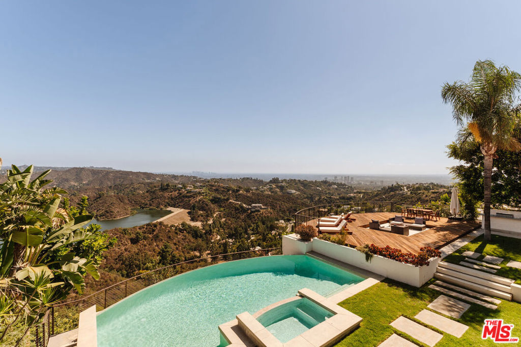 It's rare to find sweeping panoramic views and a home designed for effortless luxury but 2028 Stradella delivers it all. Tucked away on an expansive 28,000+ sq. ft. lot in the hills of Bel-Air, this 4,300+ sq. ft. residence offers the ultimate escape, where city energy meets tranquil retreat. As you walk in, you are greeted by a grand foyer with an elegant spiraling staircase, setting the tone for the entire home. Nearly every room captures commanding vistas from the shimmering Stone Canyon Reservoir to the skyline of Downtown Los Angeles, Century City, Palos Verdes Peninsula, the ocean and beyond. Spanning two levels, the home offers 4 bedrooms and 5 bathrooms, each designed with sophistication and comfort in mind. Upstairs, three bedrooms are generously sized, all en-suite, with walk-in closets and private balcony access. The primary suite is a true retreat, featuring a fireplace, spa-style bath, sitting area, and a private balcony with head-turning views. The lower level is designed for both entertaining and everyday living. A beautiful living room with oversized windows and abundant natural light flows effortlessly to the dining room, which overlooks the backyard and breathtaking views. The dining room doors accordion fully open, creating seamless indoor-outdoor living. The kitchen connects naturally to a generously sized family room, complete with sliding doors that lead out to the backyard and one of two outdoor fire pits. A convenient downstairs bedroom is perfect for guests. The backyard is the crown jewel of the residence, an entertainer's paradise featuring a sparkling infinity-edge pool and spa, over 2,000 sq. ft. deck, built-in BBQ, and two fire pits, all set against the stunning backdrop of panoramic views. A private sports court adds an active edge to this luxurious lifestyle. Additional highlights include a 3-car garage and proximity to Bel-Air's most exclusive estates, each valued at $10M+. 2028 Stradella is the ultimate expression of elevated living where luxury, privacy, and breathtaking views come together in one incomparable home.