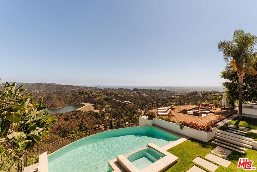 It's rare to find sweeping panoramic views and a home designed for effortless luxury but 2028 Stradella delivers it all. Tucked away on an expansive 28,000+ sq. ft. lot in the hills of Bel-Air, this 4,300+ sq. ft. residence offers the ultimate escape, where city energy meets tranquil retreat. As you walk in, you are greeted by a grand foyer with an elegant spiraling staircase, setting the tone for the entire home. Nearly every room captures commanding vistas from the shimmering Stone Canyon Reservoir to the skyline of Downtown Los Angeles,  Century City, Palos Verdes Peninsula, the ocean and beyond. Spanning two levels, the home offers 4 bedrooms and 5 bathrooms, each designed with sophistication and comfort in mind. Upstairs, three bedrooms are generously sized, all en-suite, with walk-in closets and private balcony access. The primary suite is a true retreat, featuring a fireplace, spa-style bath, sitting area, and a private balcony with head-turning views. The lower level is designed for both entertaining and everyday living. A beautiful living room with oversized windows and abundant natural light flows effortlessly to the dining room, which overlooks the backyard and breathtaking views. The dining room doors accordion fully open, creating seamless indoor-outdoor living. The kitchen connects naturally to a generously sized family room, complete with sliding doors that lead out to the backyard and one of two outdoor fire pits. A convenient downstairs bedroom is perfect for guests. The backyard is the crown jewel of the residence, an entertainer's paradise featuring a sparkling infinity-edge pool and spa, over 2,000 sq. ft. deck, built-in BBQ, and two fire pits, all set against the stunning backdrop of panoramic views. A private sports court adds an active edge to this luxurious lifestyle. Additional highlights include a 3-car garage and proximity to Bel-Air's most exclusive estates, each valued at $10M+. 2028 Stradella is the ultimate expression of elevated living where luxury, privacy, and breathtaking views come together in one incomparable home.