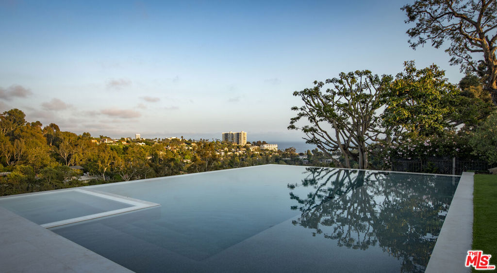 Experience unparalleled luxury living within a prestigious Pacific Palisades enclave, where this brand-new marvel stands as a testament to form and function on a rare half-acre lot with endless ocean views. Completed in 2024, the residence exemplifies California modernism with a warm, monochromatic palette highlighting sophisticated finishes like Taj Mahal slab stone, Apparatus lighting, and a host of amenities including a full spa, theater, and resort-like backyard with zero-edge infinity pool, outdoor kitchen, and private cabana. The expansive main level is set beneath soaring 12-ft ceilings and enveloped by walls of steel-framed doors allowing radiant natural light to showcase the brilliant millwork of the artisan-crafted walnut staircase and custom built-ins. From the gourmet kitchen with butler's pantry to the dining room and multiple living areas, the home is supremely appointed for grand events or intimate gatherings and lit beautifully to create an inspiring environment. Unmatched in scale and design, the primary suite is a haven of comfort beneath high vaulted ceilings and set to panoramic vistas. Complete with a sitting room, coffee bar, dual custom closets and stone-clad baths, it epitomizes a peaceful sanctuary. Descend to the lower level to experience the finest luxury amenities, from the bar, lounge, and wine tasting room to the home theater and full spa with a gym, massage room, sauna, steam room, and more. Equipped to house an elite collection of vehicles, the residence offers a 2-car and subterranean 6-car garage secured behind automatic driveway gates. Other notable features include the elevator, home automation system, private office, Wolf appliances, gunite pool and spa, a service entrance, and security system with cameras. Conveniently located between Riviera Country Club, Palisades Village, and Will Rogers State Beach, residents will enjoy convenient access to the area's premier attractions. Stately yet inviting, this exceptional residence stands as a timeless triumph of refined living, destined to be one of the Westside's most esteemed estates.