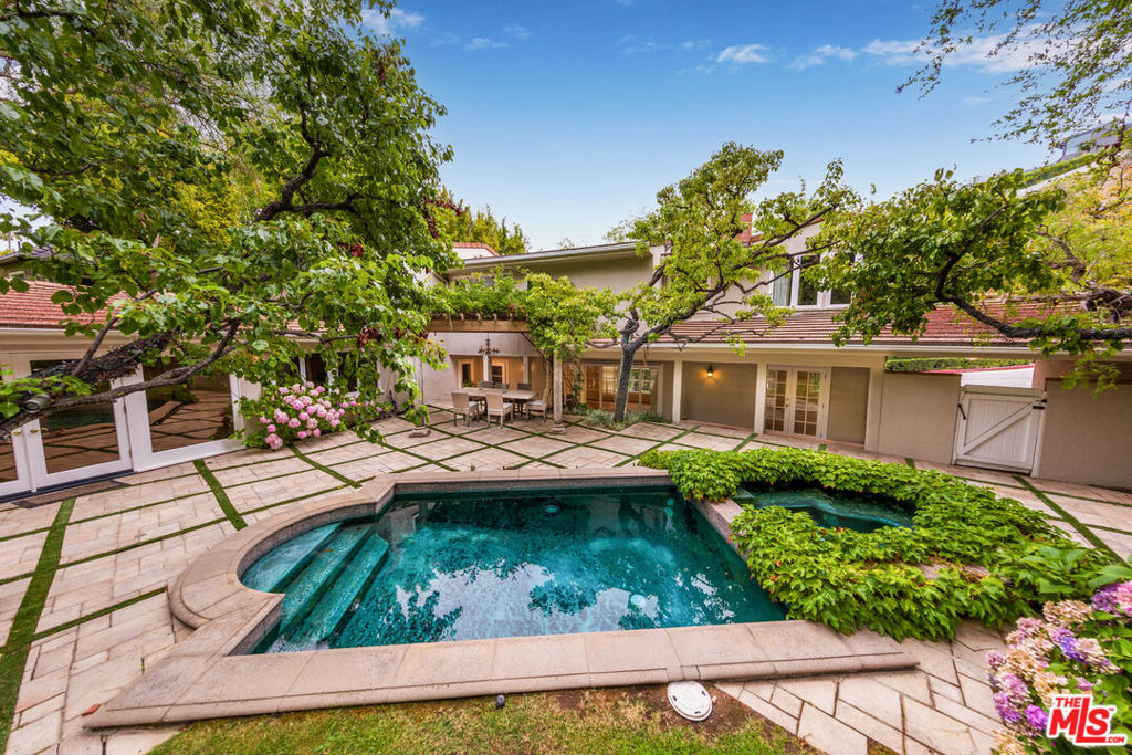 Set on a generous, private lot in lower Sunset Plaza, this timeless traditional estate offers a rare opportunity to lease a home of warmth, elegance, and historic charm. Surrounded by mature gardens and featuring a sparkling pool and spa, the property is a peaceful retreat just moments from the world-class dining, shopping, and nightlife of the Sunset Strip. Inside, the main level welcomes with a grand living room bathed in natural light, anchored by a stately fireplace and walls of windows. A richly paneled office provides a quiet workspace, while the formal dining room, complete with built-ins and a romantic balcony, sets the scene for sophisticated entertaining. The open-concept kitchen is a chef's delight, featuring a glass-door refrigerator, double ovens, and premium stainless steel appliances. It flows seamlessly into a relaxed family room, ideal for movie nights or casual gatherings. A separate housekeeper's suite adds flexibility and functionality. A beautifully preserved magnesite stairway, reminiscent of Old Hollywood glamour, leads to the upper level. The primary suite is a serene sanctuary with a private sitting area, balcony with city views, and a spa-quality bath with custom fittings and wet and dry saunas. Two additional bedrooms share a tastefully remodeled bath. Quiet, refined, and ideally located, this is Sunset Plaza living at its most classic and comfortable.