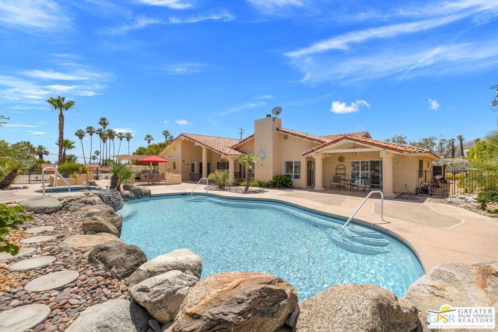 Premier location, panoramic mountain views, and exceptional pride of ownership! Welcome to 600 West Via Escuela, a one-of-a-kind 4 bed, 4 bath gated residence tucked away in the highly coveted Chino Canyon neighborhood of Palm Springs. Just minutes from scenic hiking trails and the vibrant shops, dining, and entertainment of Downtown Palm Springs, this custom home delivers a rare blend of privacy, style, and substance. Inside, soaring ceilings and expansive windows frame dramatic mountain views from nearly every room, while the open-concept floor plan creates seamless indoor-outdoor flow ideal for both everyday living and entertaining. The recently renovated gourmet kitchen is a true showpiece, boasting a vaulted ceiling, custom cabinetry with accent lighting, marble-accented solid surfaces, a dramatic 9-foot island, and a premium Sub-Zero and Wolf appliance suite including a 48" dual-fuel range with grill and griddle, multiple ovens, warming drawer, and Sub-Zero wine refrigerator. Two Bosch dishwashers, a walk-in pantry, and a separate laundry room enhance functionality, while the adjacent family room with gas fireplace and mountain views opens to a covered patio, built-in BBQ, and private pool and spa. Thoughtfully designed for comfort and versatility, the home features TWO spacious primary ensuites located on opposite ends of the residence each with mountain views, walk-in closets, private baths, and direct access to the backyard. Primary Suite One also features split vanities, a large walk-in shower, a soaking tub with mountain views, and a private water closet with an additional sink. Primary Suite Two also offers direct access to the backyard, with its private ensuite bath offering a second opening to the pool area. Junior Ensuite Three and Four each enjoy their own private baths, with Junior Ensuite Four currently styled as a home office offering stunning views. Outside, the private backyard offers multiple entertaining areas, a renovated Pebble-Tec pool and spa with newer PentAir equipment, and ample space to expand. Additional upgrades include two newer Trane HVAC systems with updated ductwork, 24 solar panels, a LifeSource whole-house water purification system, and an oversized three-car garage with built-in cabinetry. Additional gated guest parking, too! There's no HOA, no land lease, and the home is eligible for both short- and long-term rental use. 600 West Via Escuela is a rare opportunity to enjoy elevated desert living in one of Palm Springs' most sought-after neighborhoods.