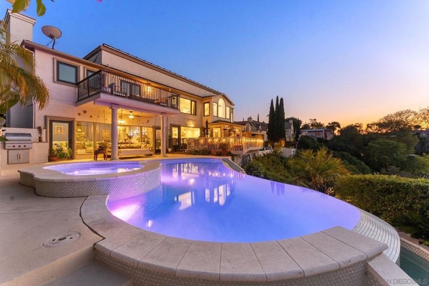 Welcome to one of Kensington’s rarest offerings—perched on a private canyon rim w/ unobstructed panoramic views that stretch from the historic Mission San Diego de Alcalá to the mountains beyond. This timeless home blends classic character with vibrant modern living, enhanced by designer finishes and the highest caliber of materials—from wood-like porcelain tile floors and custom cabinetry to architectural lighting and bespoke details that reflect thoughtful craftsmanship at every turn. Designed for both grand entertaining and everyday comfort, the home seamlessly integrates indoor and outdoor living. The infinity-edge pool appears to pour into the canyon below, anchoring a resort-style backyard complete with an outdoor fireplace, a Wolf barbecue, and multiple lounging and dining areas—all set against a backdrop of uninterrupted natural beauty. Large windows showcase the soaring views and flood the home with natural light, while custom stonework, rich crown molding, and thoughtful built-ins add character throughout. The formal living room with its statement fireplace flows effortlessly into a spacious dining room and a chef's kitchen w/ a double island, walk in pantry, and views as far as the eye can see. Upstairs, the primary retreat spans nearly the entire length of the home and serves as a true sanctuary—complete w/ a private lounge area, a spa-inspired en-suite with a soaking tub, and 2 walk-in custom closets. Additional highlights include; paid off solar w/ a Tesla battery, pool solar, and a dual-zone HVAC.