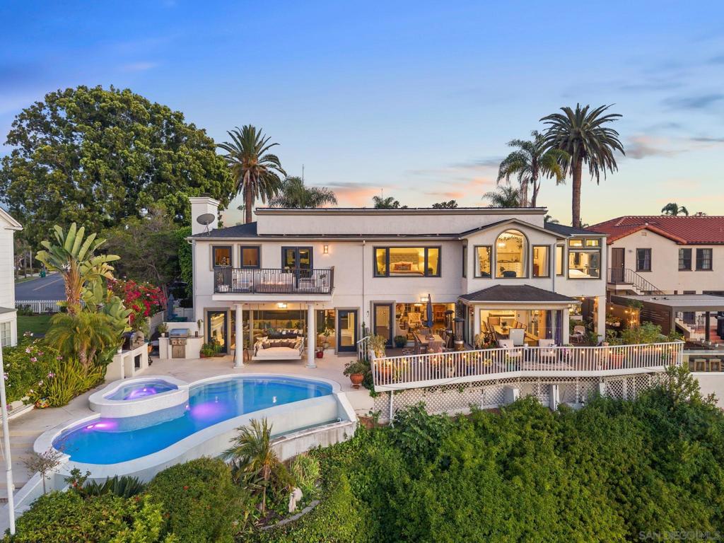 Welcome to one of Kensington’s rarest offerings—perched on a private canyon rim w/ unobstructed panoramic views that stretch from the historic Mission San Diego de Alcalá to the mountains beyond. This timeless home blends classic character with vibrant modern living, enhanced by designer finishes and the highest caliber of materials—from wood-like porcelain tile floors and custom cabinetry to architectural lighting and bespoke details that reflect thoughtful craftsmanship at every turn. Designed for both grand entertaining and everyday comfort, the home seamlessly integrates indoor and outdoor living. The infinity-edge pool appears to pour into the canyon below, anchoring a resort-style backyard complete with an outdoor fireplace, a Wolf barbecue, and multiple lounging and dining areas—all set against a backdrop of uninterrupted natural beauty. Large windows showcase the soaring views and flood the home with natural light, while custom stonework, rich crown molding, and thoughtful built-ins add character throughout. The formal living room with its statement fireplace flows effortlessly into a spacious dining room and a chef's kitchen w/ a double island, walk in pantry, and views as far as the eye can see. Upstairs, the primary retreat spans nearly the entire length of the home and serves as a true sanctuary—complete w/ a private lounge area, a spa-inspired en-suite with a soaking tub, and 2 walk-in custom closets. Additional highlights include; paid off solar w/ a Tesla battery, pool solar, and a dual-zone HVAC.