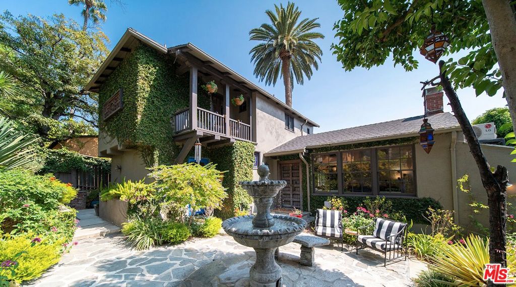Mediterranean Oasis in the heart of the city, nestled in the Hollywood Hills, offering the perfect blend of tranquil sanctuary and Old Hollywood Charm with convenient access. The beautifully landscaped gated courtyard encompasses a lush flower garden with a gorgeous patio and a classic stone fountain. Built in 1927, this artful home showcases incredible Spanish Revival design elements -- an original stained-glass window, Spanish tile throughout, and a solid stone fireplace. You'll pass through the intricately carved 18th-century wooden entryway, where you'll be engulfed by the spacious living room enhanced by a vaulted ceiling, dramatic beams, Moroccan lanterns, a striking fireplace, original hardwood floors, and a formal dining area. All that next to a tastefully renovated downstairs bathroom and an adjacent sun room with library that opens up through two sets of french doors onto the private back patio. The kitchen has been updated and offers stainless steel appliances, including a six-burner designer Wolf range, combining modern convenience with classic elegance. Upstairs, you'll find two bedrooms, a cozy balcony, and one bath providing a harmonious retreat. The rear yard is surrounded by mature hedges providing complete privacy. A native-plant garden, relaxing 8-person hot tub, larger-than-life Buddha fountain, and an additional deck create a meditative, shaded outdoor haven. Additionally, the home comes with two sizable bonus spaces that can be used as bedrooms, studios, offices, or flex spaces. The location of this home offers central proximity to major studios, renowned restaurants, and vibrant nightlife. The picturesque Lake Hollywood Reservoir is a twenty-minute hike through the hills, with iconic entertainment venues such as the Hollywood Bowl and John Anson Ford Theatre within a short distance. This one-of-a-kind sanctuary in an idyllic Hollywood Hills neighborhood has some of the most elevated, inspired aesthetics you'll find in Los Angeles! Available fully furnished with the right offer.