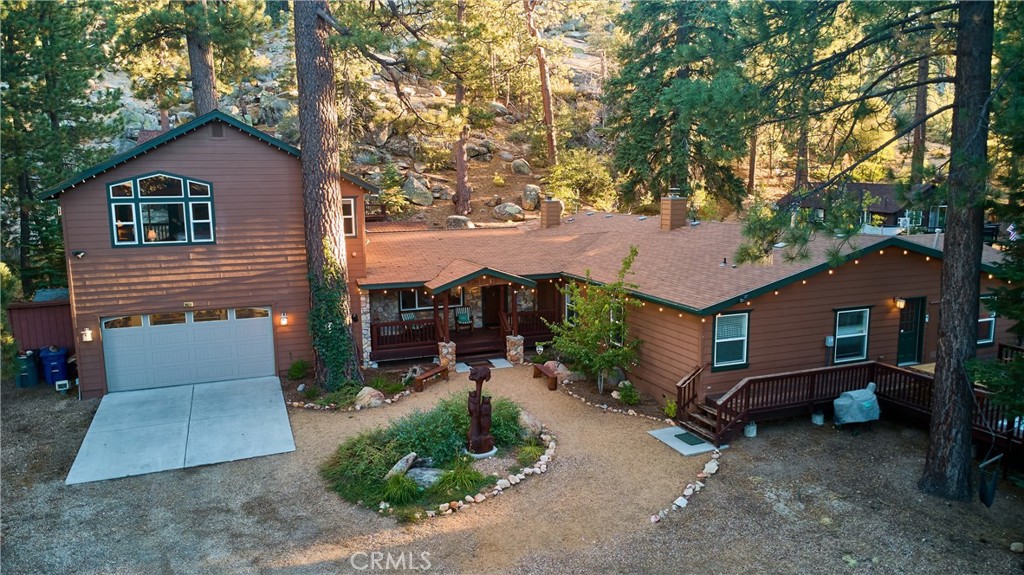 Discover one of Big Bear Lake’s most remarkable properties—an enchanting compound nestled among massive granite boulders and soaring pines, with direct access to National Forest. This extraordinary estate offers a rare blend of history, character, and modern comfort across multiple dwellings and serene outdoor spaces. At the heart of the property lies a fully restored 1920s log cabin, brimming with timeless charm. Original details, including a native stone fireplace, transport you to another era while providing a warm and intimate retreat. Tucked into the mountainside, a thoughtfully designed 430 sq ft guest house/ADU adds versatility with its cozy living/sleeping space, kitchenette, loft, and ¾ bath. The expansive main residence is designed for both privacy and gathering. The secluded East wing features a luxurious primary suite complete with a covered deck, jetted tub, and separate shower. On the West wing, three ensuite bedrooms and a flex bunk room provide abundant space for family and guests. The grounds are truly one-of-a-kind, offering countless opportunities to unwind or entertain. Multiple decks, outdoor firepits, and natural gathering areas create a seamless connection with the forested surroundings. Perhaps the crown jewel is the hike-to log gazebo, perched high above with breathtaking 180-degree views of the lake and valley—an inspiring spot for meditation, reflection, or simply soaking in Big Bear’s beauty. Whether enjoyed as a legacy property, a mountain retreat, or a distinctive investment, this compound is a rare opportunity to experience Big Bear Lake at its most magical.