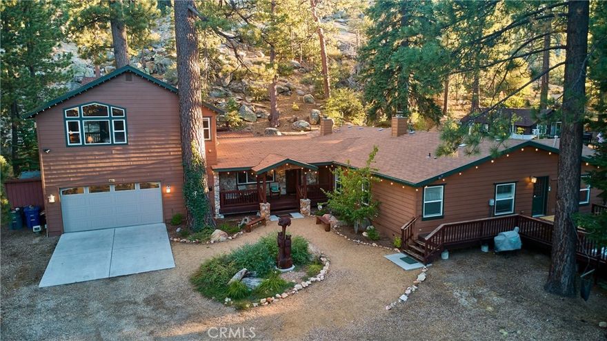 Discover one of Big Bear Lake’s most remarkable properties—an enchanting compound nestled among massive granite boulders and soaring pines, with direct access to National Forest. This extraordinary estate offers a rare blend of history, character, and modern comfort across multiple dwellings and serene outdoor spaces. At the heart of the property lies a fully restored 1920s log cabin, brimming with timeless charm. Original details, including a native stone fireplace, transport you to another era while providing a warm and intimate retreat. Tucked into the mountainside, a thoughtfully designed 430 sq ft guest house/ADU adds versatility with its cozy living/sleeping space, kitchenette, loft, and ¾ bath. The expansive main residence is designed for both privacy and gathering. The secluded East wing features a luxurious primary suite complete with a covered deck, jetted tub, and separate shower. On the West wing, three ensuite bedrooms and a flex bunk room provide abundant space for family and guests. The grounds are truly one-of-a-kind, offering countless opportunities to unwind or entertain. Multiple decks, outdoor firepits, and natural gathering areas create a seamless connection with the forested surroundings. Perhaps the crown jewel is the hike-to log gazebo, perched high above with breathtaking 180-degree views of the lake and valley—an inspiring spot for meditation, reflection, or simply soaking in Big Bear’s beauty. Whether enjoyed as a legacy property, a mountain retreat, or a distinctive investment, this compound is a rare opportunity to experience Big Bear Lake at its most magical.