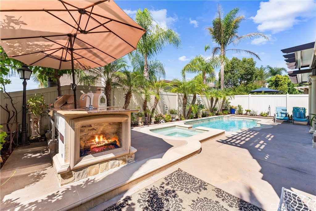 Timeless, romantic, and immaculate, this European influenced estate in Serrano Heights is a dream come true! No expense was spared on creating this stunning Mediterranean-style home. Towering cypress trees, numerous palms, and blooming flowers will greet you happily upon your arrival. As you walk to the front door, the smooth stucco walls, the handsome stone frames around the doors and windows, and the keystones with a carved shell motif give you a sense of nostalgia. Inside, a charming foyer, a cozy living room, and a formal dining room welcome you! Open to the family room with an elegant fireplace, the kitchen is a chef's dream. It boasts a central island with antique finish cabinetry, glass paneled cabinet doors, stainless steel appliances, under counter lights, 3 cm quartz countertops, and full stone/glass backsplash. Next to the kitchen, a good sized den can be turned into a bedroom easily. Fully upgraded, the bath downstairs features a classic vanity with a marble countertop, travertine walls, and a travertine shower with a custom soap box. Upstairs, the primary suite showcases a covered balcony with travertine tile floor-perfect for you to unwind and enjoy the spectacular sunset views after work! The primary bath's highlights include granite countertops, a soaking tub, a granite walk-in shower, dual vanities, a makeup vanity, and a huge walk-in closet with a closet organizer. 2 secondary bedrooms with walk-in closets share a jack-and-jill bath which also has antique finish cabinets, 3 cm quartz countertop, and stone mosaic backsplash. The 3rd bath upstairs is located between the 4th bedroom and the tech center which offers a built-in desk and a beautiful chandelier. Just professionally cleaned and sealed, the gorgeous lime stone floor flows through downstairs. Durable solid oak floor on the staircase and upstairs. Classic plantation shutters. Countless dazzling chandeliers. Beautiful crown moldings. Built-in cabinets, overhang racks, and a water softener in the garage. A custom wrought iron gate with scrolls. Newer vinyl fences. Lush, comfortable, and mesmerizing, the yard will make you fall in love with it. Watch water from the raised spa flow into the pool, swim in the freeform Mediterranean pool, warm up by the fire glass fireplace, relax in the oversized covered patio with Tuscan-style columns, bake your homemade pizza in the outdoor pizza oven--truly a resort living experience in a Mediterranean like villa! Move-in ready! Don't miss out!