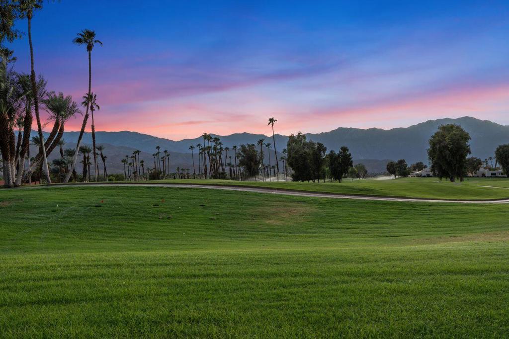 Welcome to Mission Hills Country Club, where spectacular mountain peaks and lush fairways frame your everyday views. Perfectly positioned on the 13th hole of the famed Tournament Course, this beautifully upgraded residence offers the ultimate blend of comfort, elegance, and resort-style living. Enter through a spacious, private courtyard enhanced with custom pavers and lush landscaping an ideal spot for morning coffee or evening gatherings under the desert sky. Inside, soaring wood-beamed ceilings, rich travertine flooring, and a dramatic stacked stone fireplace create a warm and inviting living room, where walls of glass draw your eye to the breathtaking panorama of golf course greens set against the rugged San Jacinto Mountains. The open-concept kitchen and dining area are designed for both style and function, featuring custom cabinetry, upgraded appliances, a built-in desk, and seamless access to the courtyard for alfresco dining. A dry bar with a wine refrigerator adds the perfect touch for entertaining guests. The primary suite is a private retreat with sweeping views, custom built-ins, patio access, and a spa-like remodeled bath with walk-in shower and custom closet. The guest suite, complete with its own updated bath, ensures comfort for family and friends. The converted golf cart garage offers a versatile bonus space ideal for a home office, game room, or creative studio. This home also features a newer AC unit. Just steps from the sparkling community pool and spa, this home also comes with the perks of Rancho Mirage residency, including discounted golf at the world-class Pete Dye and Gary Player courses, plus access to fine dining, tennis, spa facilities, and fitness at the Westin Mission Hills Resort. Here, every day feels like a vacation.