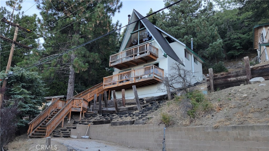 Welcome to 1933 Willow Drive, where you'll feel on top of the world! This popular A frame style cabin has panoramic views of the ocean, Mt Baldy, the Inland Empire valley, Anaheim Hills and everything in between.
With coveted vaulted ceilings in the living room and loft area, this cabin is the epitome of chalet living. Large picture windows showcase the gorgeous views and a Swedish fireplace will keep you toasty on winter nights. There's a bedroom on the main floor, as well as a full bathroom. Downstairs is a game room/family room or additional sleeping space, you choose! Three nice sized decks make comfortable outdoor seating to enjoy too.