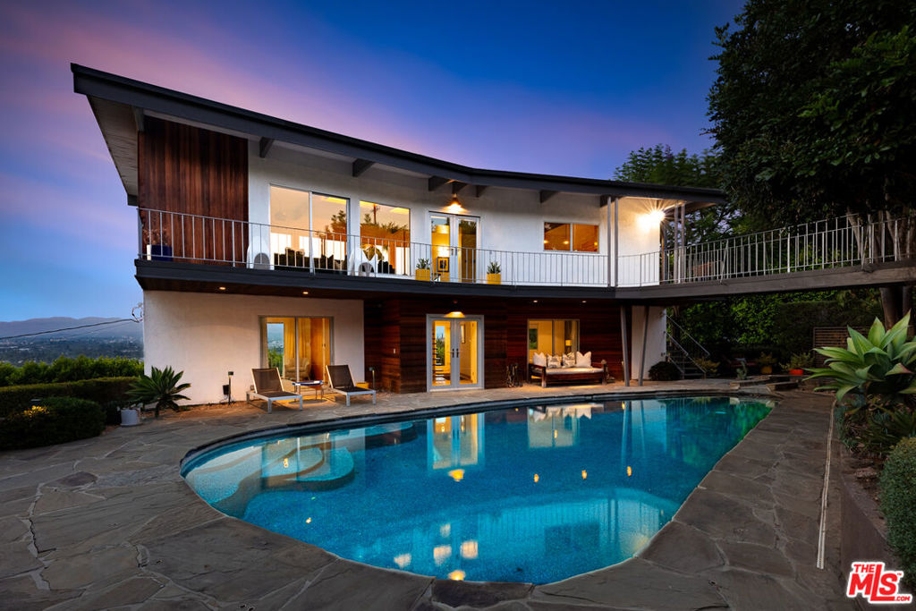 PRIVATE HILLSIDE COMPOUND WITH UNOBSTRUCTED VALLEY VIEWS. Reimagined mid-century sanctuary on coveted north-facing Berry Drive. This exclusive mini compound offers A-list privacy with jetliner views stretching across the entire San Fernando Valley. Soaring 80 inch floor-to-ceiling glass walls frame every sunset like art. The chef's kitchen, outfitted with premium appliances, doubles as a personal observation deck. Authentic wood-beamed ceilings and seamless indoor outdoor flow create a voluminous, loft-like atmosphere. Step outside to resort-style living featuring a dramatic dark bottom pool, elevated spa, and tranquil waterfall surrounded by lush, manicured landscaping on a 10,000+ square foot lot. Bonus: Two detached guest bungalows, an ADU and ALQ, each with its own private entrance, kitchenette, and full bath. Ideal for guests, multi-generational living, or passive income. Tucked in the heart of Studio City Hills' most exclusive enclave. Just minutes to Ventura Boulevard's premier dining and shopping while offering complete serenity and seclusion. A rare offering where every window captures a masterpiece and every detail whispers retreat.