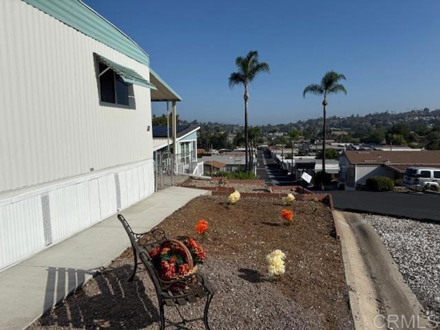 Back on the market due to Buyer not being approved by the park. Welcome to your new home! This beautifully updated 2-bedroom, 2-bath residence is located in a secure, well-maintained 55+ community that is resident-owned, ensuring a peaceful living environment with extremely low monthly space rent. Step inside to discover an inviting open concept layout that seamlessly connects the living room, dining area, kitchen, and den, perfect for entertaining or relaxing. Recently painted interior offers a clean, updated look. Ceiling fans in the living room and bedrooms provide comfort throughout the seasons. The Primary bedroom features a spacious walk-in closet and a bathroom equipped with a double vanity, an additional vanity, and a linen closet. The second bathroom has been recently updated with a new tub enclosure, faucet, and fixtures. The OnQ system provides home technology systems and structured wiring products. Enjoy your morning coffee or unwind in the evenings on the screened porch or patio, where you can take in stunning city and mountain views. The community offers excellent amenities, including a pool, spa, recreation center, dog park, and laundry facilities if needed. For your convenience, this home also includes a stackable washer and dryer. Outside, you'll find two storage sheds, perfect for keeping your tools and outdoor equipment organized. The carport accommodates two vehicles, with an additional open space available for a third.
