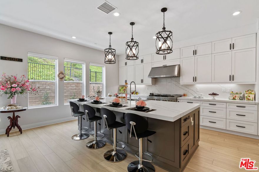 Located within Montebello's prestigious guard-gated Metro Heights community, this thoughtfully curated Toll Brothers residence redefines modern hillside living through an effortless blend of contemporary design, lifestyle flexibility, and resort-style amenities. Set across three levels, the Outlook Elite offers a balance of refined materials and inviting spaces, designed as much for daily comfort as for elevated entertaining. A soaring three-story foyer welcomes you into a home where every space has intention. Just beyond, the living room centers around a sleek modern fireplace, framed by natural light and warmth. French doors open directly to the outdoor living area, creating the perfect setting for al fresco dining, weekend lounging, or gathering under the stars. The kitchen, thoughtfully positioned at the heart of the home, features clean lines and high-end JennAir appliances. Quartz countertops, a walk-through pantry, and direct access to the formal dining room offer both functionality and sophistication. Every surface has been carefully selected, with finishes that reflect a quiet sense of luxury. With five bedrooms and seven bathrooms, the layout is designed for privacy, versatility, and ease. On the main floor, a guest suite doubles as an ideal office, tucked away for focus yet easily accessible. Upstairs, the primary suite serves as a peaceful retreat with a generous walk-in closet and a spa-inspired bathroom that includes a deep soaking tub, dual vanities, and a rain-style shower surrounded by porcelain tile. Two additional bedrooms feature en-suite baths, while a third shares a beautifully appointed hall bath. An open loft provides additional space for reading, working, or relaxing. On the third level, a flexible family room opens to a covered balcony with sweeping views, offering the perfect space for a home theater, game lounge, or creative studio. Every inch of the home is finished with thoughtful details including handcrafted tilework, premium quartz surfaces, and a cohesive, timeless material palette. Outside, the Metro Heights lifestyle unfolds. Residents enjoy access to a private clubhouse, resort-style pool and spa, state-of-the-art fitness center, and elegant social lounges. Scenic walking trails and lush landscaped paths weave throughout the community, offering panoramic city views and peaceful green spaces that make everyday living feel extraordinary. Additional features such as a whole-home water softener, a solar panel system, and full interior insulation reflect the home's commitment to efficiency and comfort. Rarely does a new construction home offer this level of intention, design, and community. This is more than a home. It's the beginning of your next chapter in Montebello's most desirable hilltop enclave.