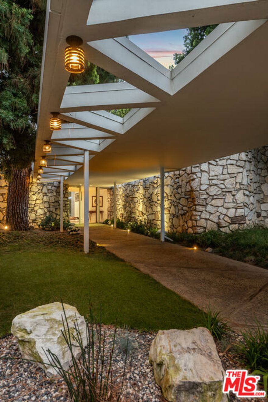 A true architectural gem by master architect A. Quincy Jones, AIA, this mid-century masterpiece is nestled in the heart of Beverly Hills on a rare street-to-street 1.2-acre lot north of Sunset. Exemplifying timeless California modernism, the home showcases original mid-century details including iconic floor-to-ceiling glass walls that flood the interiors with natural light, terrazzo flooring, fieldstone accent walls, and a classic step-down bar. The open-concept layout seamlessly connects expansive living and dining spaces to multiple patios and outdoor spaces, ideal for effortless indoor-outdoor living. The primary suite offers a serene retreat with a cozy fireplace, dedicated relaxation lounge, and a spa-inspired bath, all opening to a lush, park-like backyard complete with a swimmer's pool and N/S tennis court. A thoughtfully designed two-unit guest house complements the original architecture, providing additional space and privacy while honoring the legacy of Jones' vision. This is a rare opportunity to own a residence that combines architectural integrity and historic significance.