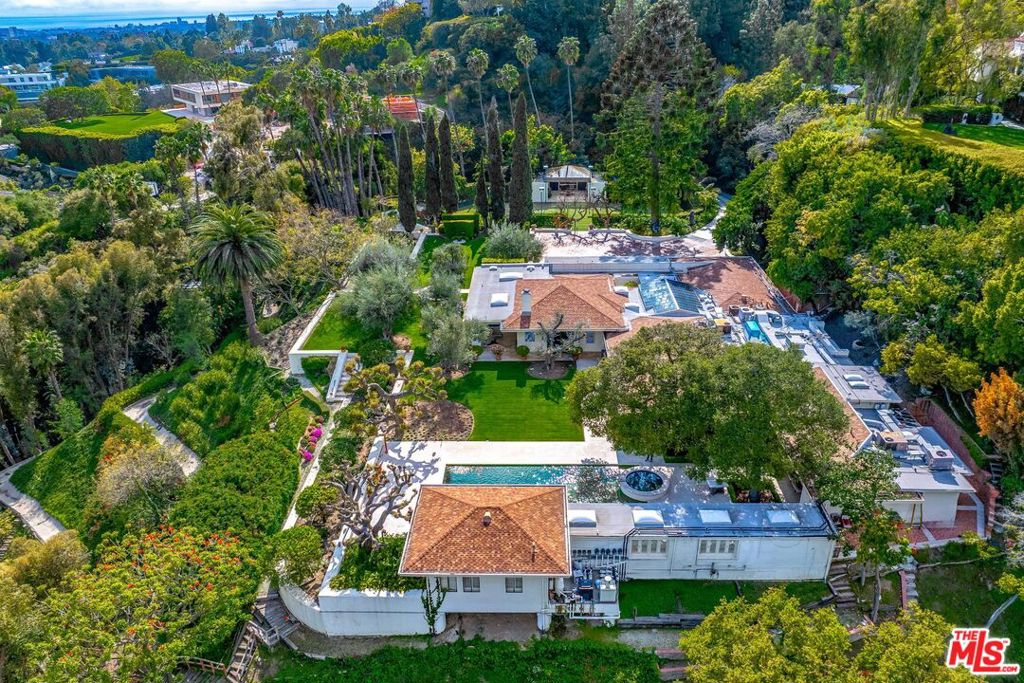 This stunning property, of extremely rare scale, directly overlooks the Bel-Air Hotel and is perched on a commanding parcel with sweeping city views. The property is comprised of 3.6 acres, approximately 2 acres flat, featuring a long private driveway and exceptional privacy. This offering includes plans for an absolutely staggering 27,000 sq ft architectural marvel of uncompromising luxury, with the added bonus of grandfathered-in specifications that are exempt from recently introduced building ordinances. The massive and highly buildable lot also features a 5-bedroom home that exceeds 7,500 square feet, boasting spectacular lawns, meandering pathways, pool, spa, stunning gardens and outdoor entertaining areas. This truly is a benchmark-setting estate in one of the most revered locations in all of California.
