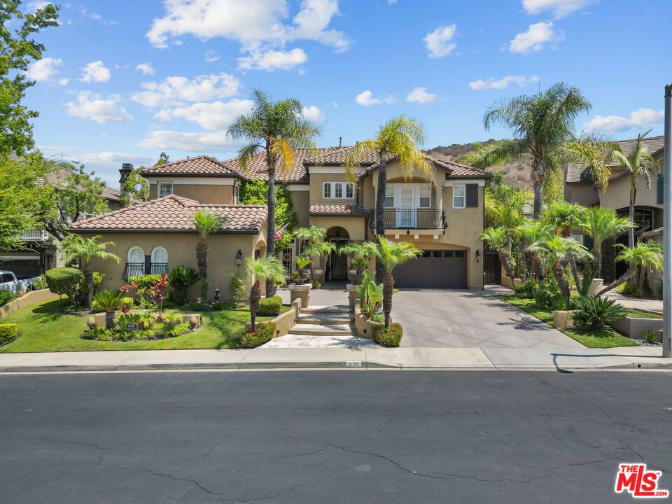 Welcome home to The Oaks. This luxurious Mediterranean-inspired two-story, 5-bedroom, 5-bath, 3,983 sq. ft. residence sits on an 8,365 sq. ft. lot, nestled in a quiet cul-de-sac surrounded by lush landscaping and beautiful mountain views in the exclusive gated community of Wood Ranch. As you step into the impressive foyer, you're welcomed by an abundance of natural light streaming through expansive windows and soaring ceilings. The attention to detail is evident with custom moldings, exquisite woodwork, and beamed ceilings that enhance the character of each room. Recent custom upgrades include solar with two Powerwall backup batteries & upgraded inverters for additional backup capability, Pottery Barn Remington Collection chandeliers, a fully custom-designed and integrated smart home system with Control4 operating system, Sonos surround sound, Luma camera surveillance system, Philips Hue light fixtures, custom fireplace design, and fresh interior paint. The gourmet kitchen offers custom cabinetry, wine cooler, bar area, walk-in pantry, center island, Viking stove, and Sub-Zero refrigerator, truly a chef's delight. Hardwood flooring spans the first level, which also features a formal dining room recently reimagined with exquisite detail. A versatile downstairs suite with en-suite bath is ideal for use as a private office, gym, or guest quarters. The grand staircase leads to a spacious loft overlooking the first level and offering serene backyard views. The master retreat provides spa-like amenities, including a lounge area with fireplace, dual walk-in closets, and dual vanities. The backyard is an entertainer's dream, designed for gatherings and outdoor living. Highlights include a covered outdoor kitchen with built-in gas BBQ and bar seating, gazebo, lounge area with fireplace, pool with AquaLink lighting and fountains, a custom pool net cover, hot tub, and plenty of space for dining and relaxation. Don't miss this opportunity to own a stunning home in one of Simi Valley's most sought-after communities.