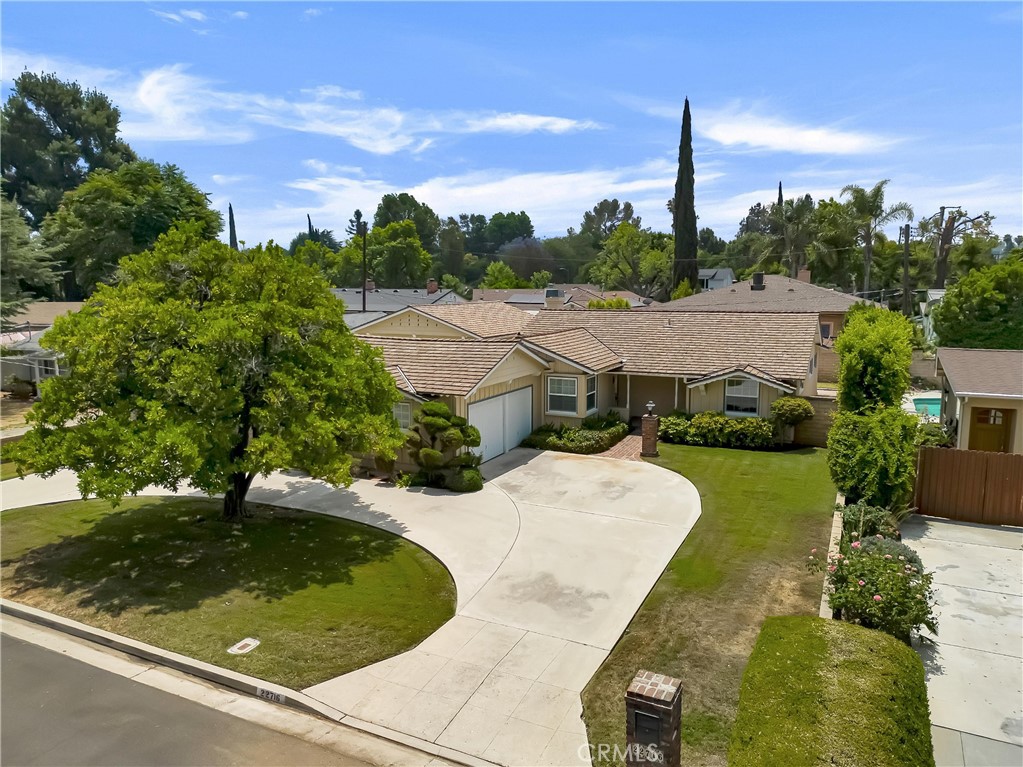 Wonderfully maintained and updated 3 bed, 2.5 bath, ranch-style home in quiet residential neighborhood in Woodland Hills. Set on a spacious, nearly 10,000 sq ft lot, the home has great curb appeal with a circular drive, mature citrus tree, grassy lawn, and a brick walkway leading to a covered front porch. This home blends timeless character with thoughtful upgrades including hardwood floors, crown molding, recessed lighting, dual pane windows, and stylish touches throughout. Formal entry leads to an appealing living room with exposed beam ceilings, a cozy brick fireplace with raised hearth, and French doors out to the back patio. The adjacent formal dining room features decorative wainscoting, a built-in sideboard, and flows effortlessly into the updated kitchen, sporting Corian counters, white cabinetry with convenient roll outs, stainless steel appliances including a double oven and a sunny breakfast nook. Beyond is a sizable utility room, converted from half of the attached garage, with abundant storage, laundry, utility sink, and natural light from a skylight, with direct access to the yard and remaining attached garage space. Down the hallway, boasting decorative chair rails, are three well-appointed bedrooms. The primary suite features a coved ceiling, with exposed beams, a huge walk-in closet, and a beautifully updated ¾, en-suite bath. The other two bedrooms share an updated, full, Jack-and-Jill bath and one has a built-in wardrobe and direct access to the back yard. Additional features include beautifully updated powder bath for guests’ convenience and emergency generator. Outside, the large lot includes a sizable, covered patio, lawn area, and sizable concrete area behind a secured gate which would be used for additional parking and leads to a fully permitted 723 sq ft detached garage. The 20’10”x30’ garage structure offers an extra tall RV door, attic storage, built-in cabinets, and workbench, and could be converted into an ADU for additional income or multigenerational living. Well situated near Woodlake Charter Elementary School, shopping, dining, entertainment, and recreation as well as major transportation thoroughfares and within easy distance to playground, recreation center and farmer’s market. This home offers both elegance and utility in one package, don’t let it pass you by.
