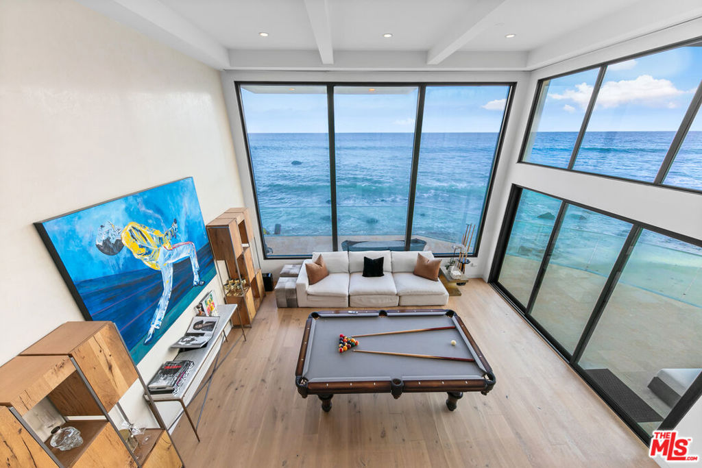 Experience Malibu living at its finest on iconic Malibu Road. This prestigious property, a former celebrity-owned beachfront retreat, is a breathtaking coastal sanctuary offering sweeping ocean views that stretch from Santa Monica and Palos Verdes to Catalina and Point Dume. A dramatic entryway makes a jaw-dropping impression, framed by landscaped front and back courtyards. Towering two-story ceilings and complete privacy elevate the living experience, while expansive outdoor spaces invite both serenity and entertaining. Inside, rich oak hardwood floors flow throughout. The gourmet kitchen stuns with creamy white cabinetry, luxurious finishes, and a layout designed for both beauty and functionality. The oceanfront primary suite is a true retreat with a cozy fireplace, dual walk-in closets, and panoramic views. The spa-like primary bath features a soaking tub, oversized steam shower, and direct ocean views. Upstairs, two guest bedrooms share a dual bathroom, offering both comfort and privacy. Outdoor living is unmatched, with a rare and expansive entertaining area complete with a built-in BBQ and private spa. The main house offers four bedrooms plus an office/den, while a completely separate one-bedroom guest house with its own ocean views sits across the courtyard. This iconic, exquisitely designed property is truly one of Malibu's finest, and can be sold fully furnished.