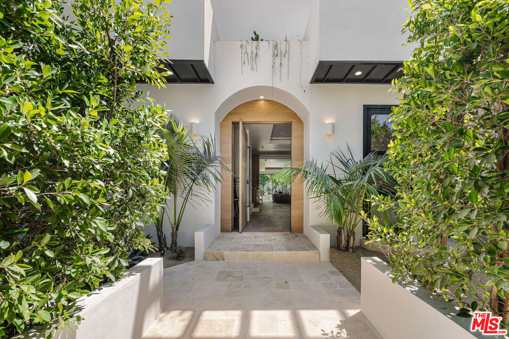 Discover a meticulously reimagined sanctuary where Tulum inspired elegance meets relaxed sophistication. Situated in the heart of Beverly Grove, this gated architectural masterpiece seamlessly blends modern design with effortless luxury. Spanning over 5,300 SF of indoor-outdoor living, the home features a gourmet kitchen with Miele and Leicht appliances, an oversized island, and pocket sliding doors that connect bright interiors to lush outdoor spaces.Featuring four spacious bedrooms and six luxurious bathrooms, this home includes a stunning primary suite with a cozy fireplace, a large private balcony, custom walk-in closets, and a sleek spa-inspired bathroom with a freestanding soaking tub. The second floor offers a charming outdoor terrace, leading to a rooftop deck complete with a built-in wet bar and breathtaking 360-degree views. Enhanced by a state-of-the-art Control4 home automation system, this residence effortlessly combines comfort and modern sophistication.