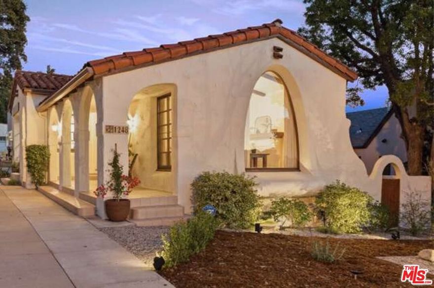 Set along a quiet street in Prime Rossmoyne, just three doors below Mountain St. this three bedroom, two bath 1928 Spanish Revival home introduces itself through a series of deep arches that define the front porch. Textured plaster and curved openings provide an immediate read on the home's architectural heritage.The living room expands that impression. The space is large and airy, shaped by a vaulted ceiling and original wood beams. A prominent arched window at the front draws in generous light and reinforces the home's period character. The fireplace offers a grounded focal point, framed by niches that echo the curves found throughout the house.The dining area sits just off the living room, framed by broad archways that keep the rooms connected. Terracotta flooring sets a warm foundation, and French doors lead you outside, providing a clear view and easy backyard access. The kitchen is beautifully updated, offering ample workspace and a clean connection to the home's main gathering areas while respecting the architecture around it.All three bedrooms are well proportioned, each with ample natural light and a comfortable sense of privacy. One bedroom opens out directly to the ideal backyard. Outdoors, ficus trees and drought-tolerant landscaping form a large, private garden with room for both everyday use and larger gatherings. A detached two-car garage sits at the rear of the property.Modern upgrades support the home without distracting from its period character. Fully owned solar panels, a whole-house water softener, a Level 2 EV charger and a bolted and braced foundation add practical, long-term value.The home sits within the highly sought-after Rossmoyne neighborhood, known for its tree-lined streets, architectural continuity and well-preserved historic homes. Blocks away from Nibley Park Trader Joe's and Whole Foods Market,  Rossmoyne is a place with a warm, welcoming vibe, the kind of neighborhood you'll be glad to call home.