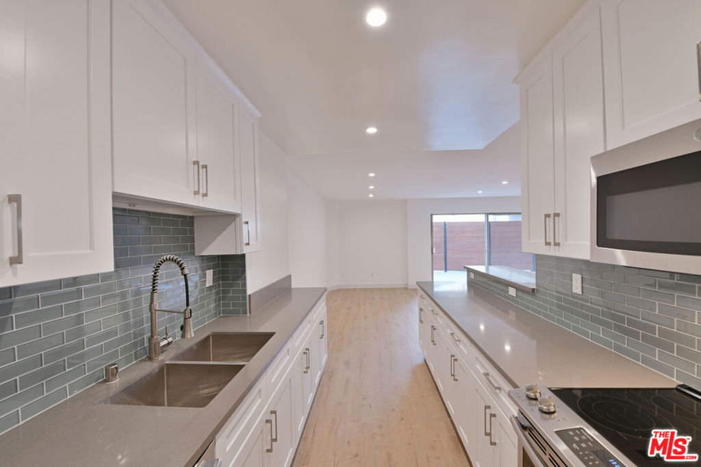 This modern 1 bedroom apartment features an open concept living area with wood style flooring, recessed lighting, and a beautifully updated kitchen with quartz countertops, sleek cabinetry, and a stylish glass tile backsplash. Large sliding doors lead to an oversized private patio, perfect for entertaining or relaxing outdoors. Freshly renovated and filled with natural light, this home offers a comfortable layout with contemporary finishes in a prime location.