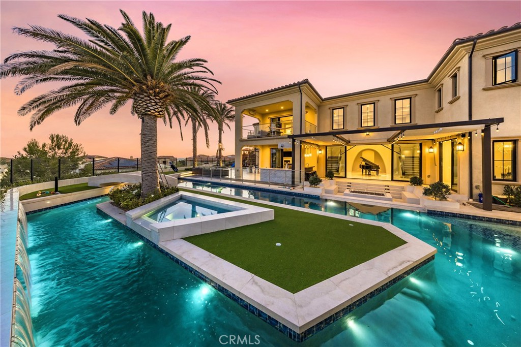 ***Private Resort Estate*** Modern Architectural Gem nestled on a EXCLUSIVE prime CORNER lot with breathtaking mountain and OCEAN VIEWS w/ vistas of Catalina Island. This 5-bedroom haven w/ Open Air POOL HOUSE w/ Bathroom redefines opulence with its resort-inspired outdoor oasis and meticulously crafted interiors, offering a lifestyle of sophistication and leisure.
Resort-Style Outdoor Amenities allow you to dive into a swimmer’s paradise featuring a LAZY RIVER powered by a state-of-the-art PENTAIR INTELLICENTER and a commercial RIVER FLOW SYSTEM. Olympic-length lap pool, an INFINITY WATERFLOW cascading next to a modern SUNKEN FIREPIT, two BEACH-designed pool BAJAS for ultimate relaxation. A glass tile JACUZZI and FUJIWA JAPANESE-painted tiles elevate the poolscape, while a CURB FRONTAGE LINED WATERWALL and PILASTER fountains create a grand flowing entrance. Stay active with an in-ground BASKETBALL HOOP, a PUTTING/CHIPPING GREEN as you cross over the Lazy River via a mini-BRIDGE onto a 4-HOLE GOLF course island under a lush CANARY PALM. Unwind in the 7’ DUNDALK PANORAMIC VIEW CEDAR BARREL DRY/WET SAUNA, designed for ultimate relaxation. Two OUTDOOR SHOWERS and a convenient pool house restroom ensure comfort for guests. Landscaping includes 6 MEDULLA PALMS in addition to the Canary palm, complemented by a 30 foot wide water feature fountaining into the river. The OUTDOOR KITCHEN boasts a fully loaded ALFRESCO GRILL system with Sear Zone, 24-inch WOK burner, and built in refrigerator. HEATED PATIOS (Up&Down) with views of the ocean, perfect for year-round gatherings.
Interior features boast a DUAL GOURMET KITCHENS: A state-of-the-art main kitchen featuring premium WOLF appliances, complemented by a prep kitchen showcasing airy cloud-designed quartz backsplash for fanciful cooking. Opulent Interiors: White marble and natural hardwood floors create a timeless ambiance, enhanced by a sleek, upgraded glass stairwell with contemporary glass railings. Spa-Inspired Master Bath: Fully clad in marble, equipped with 100% Kohler water systems for ultimate luxury. Breathtaking Views: Five floor-to-ceiling sliding glass doors flood the home with natural light, offering spectacular eastern sunrise vistas. Thoughtfully designed CORNER lot views of mountain and ocean from all corners of the property w/ tranquil evenings by the INFINITY WATERFLOW to lively gatherings under the canopy. ***ULTRA RARE*** PRIVATE RESORT with unmatched luxury and coastal charm.