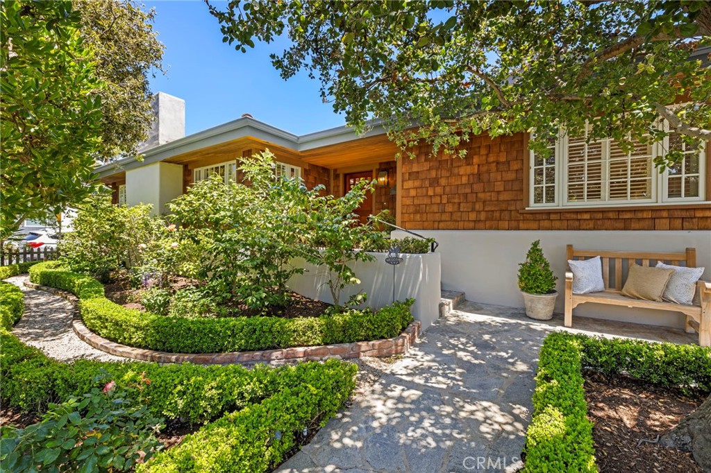Tucked within Laguna Beach’s coveted Crown Point neighborhood, 169 McKnight is a rare single-level coastal home that invites you into a world of timeless beauty and effortless living. Located on the ocean side of Pacific Coast Highway and just blocks from Crescent Bay Beach, one of Laguna’s most beautiful coves, this home is surrounded by mature trees, lush landscaping, and a garden setting that feels peaceful, private, and distinctly coastal.
Lovingly maintained and thoughtfully designed, this shingled home blends indoor comfort with outdoor serenity. The living spaces center around a sun-filled courtyard that welcomes coastal breezes and natural light, creating an intimate setting for dining, entertaining, or simply enjoying the flow of everyday life. Inside, high tongue and groove wood ceilings, rich hardwood floors, and a classic wood-burning fireplace add warmth and character throughout. Two guest bedrooms sit just off the main living space, one with built-in workstations ideal for creative pursuits or remote work. They share a beautifully updated bath with timeless finishes. The spacious primary suite is a private haven with its own access to both the courtyard and a tranquil backyard garden. The en-suite bath features dual vanities, a soaking tub, and an oversized walk-in shower that complements the home’s elevated coastal style.With its thoughtful layout, enduring style, and enviable proximity to everything that defines the Laguna Beach experience, 169 McKnight is just minutes from Crescent Bay Beach, downtown, acclaimed restaurants, art galleries, and boutique shops. This coastal gem in one of Laguna’s most sought-after neighborhoods offers a timeless setting to enjoy the very best of Laguna Beach living.