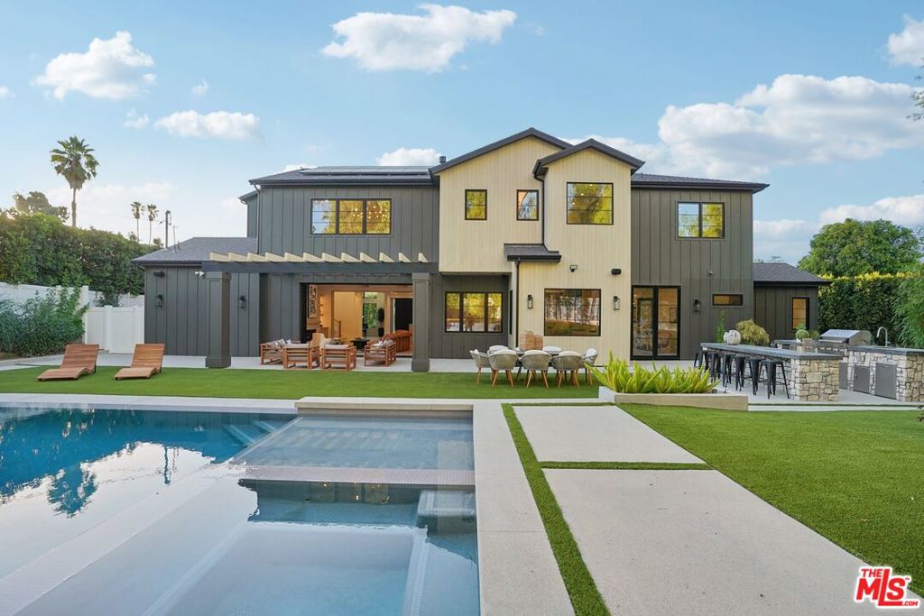 Discover the pinnacle of luxury in this newly constructed gated estate located South of the Boulevard in the heart of Tarzana, CA. Built with the finest materials and high-end designer finishes, this secluded residence offers an exceptional living experience combined with the convenience of all the Valley has to offer. On the first floor, step through the oversized front door into an open-concept layout flooded with natural light from expansive windows and adorned with soaring ceilings. The living room, featuring a fireplace and two-story vaulted ceilings with exposed wood beams, exudes elegance. The formal dining room, perfect for hosting dinner parties and gatherings, is highlighted by a stunning wood slat ceiling.The gourmet kitchen is a chef's delight, boasting a massive center island with a breakfast counter, top-of-the-line appliances, a walk-in pantry, and a cozy breakfast nook. Adjacent to the kitchen, the family room offers a beautiful stone fireplace, built-in cabinetry, coffered ceilings, and a pocketing glass door that transitions effortlessly to outdoor living. Also on the main level, find a downstairs ensuite bedroom, an office with built-ins and a French door leading outside, a laundry room, a mudroom, a movie theater, and a dry bar with a wine fridge. The backyard is a true oasis, featuring multiple pergolas, a fully equipped summer kitchen with bar seating, a sports court, and a pool/spa with a reverse infinity waterfall. A pool house with a bathroom and a fire pit with built-in seating complete the outdoor amenities.Ascend to the second floor, where a teen loft and three ensuite bedrooms with walk-in closets provide ample space and privacy. The luxurious master suite is a sanctuary of comfort, featuring vaulted ceilings with exposed wood beams, a fireplace, dual walk-in closets, and a lavish bathroom with a soaking tub, a spacious shower with a rainfall system, double vanities, and a private water closet.Additional amenities include a three-car garage and abundant storage throughout the home. Don't miss this rare opportunity to own a meticulously designed estate that perfectly balances luxury and comfort.