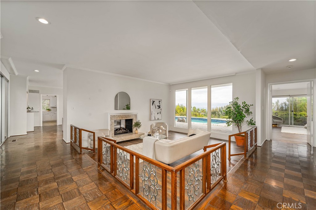 Welcome to 20193 Adele Drive, a stunning Hollywood Regency-inspired retreat tucked away in the hills of Woodland Hills, south of the boulevard. This unique single-story residence blends timeless 1970s design with unforgettable views and serene, resort-style living. As you step through the first door, you're greeted by a peaceful atrium, a beautiful introduction to what lies beyond. The second entry brings you into a dramatic open living space, where floor-to-ceiling glass windows immediately draw your eyes outward. The view is absolutely breathtaking, offering sweeping vistas of the city and mountains beyond, a daily reminder of California living at its best. While the home is not officially attributed to architect John Elgin Woolf, its design reflects the elegance and drama of the Hollywood Regency style he helped define. Bold lines, natural light, and thoughtful architectural elements give this home a character all its own. Inside, you'll find a spacious primary suite and two additional generously sized bedrooms, offering comfort and privacy. The formal living room, complete with a cozy fireplace, is perfect for entertaining or relaxing with guests. Step into the private backyard oasis, where a glistening pool sparkles in the sun and mature landscaping surrounds you in total tranquility. It’s the kind of space that instantly makes you feel like you're on vacation, every day. With 2,800+ sqft of living space on a large, peaceful lot, this home offers architectural charm, modern comfort, and an unbeatable location in one of Woodland Hills’ most desirable neighborhoods.