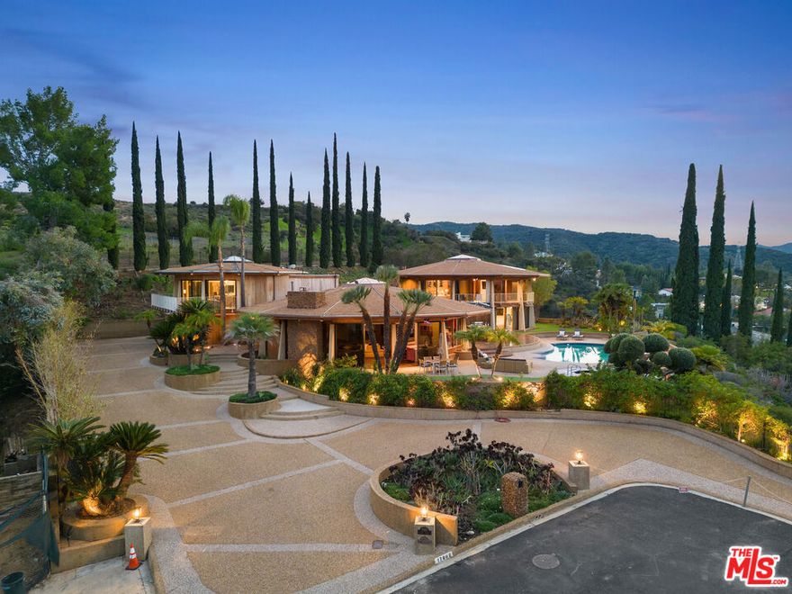 his property is available for  long-term rentals. It is fully furnished, decorated, and equipped with hotel-like essentials and amenities. With our concierge team available to assist 24/7, this home rental offers a five-star hospitality experience.Nestled within the San Fernando Valley, the Lewis-Loughrey Estate stands as a testament to mid-century modernist architecture, boasting nearly 7,000 square feet of meticulously designed space. As you enter through the original bronze-clad Sunburst door, the home unfolds into three remarkable dodecagons, housing a total of seven beds and six baths. The seven bedrooms, each uniquely designed, offer breathtaking views and plush accommodations, with the main house featuring five bedrooms and the guest house offering two ensuite bedrooms. The state-of-the-art kitchen, adorned with updated appliances and ample counter space, leads to a formal dining room, seamlessly blending indoor and outdoor living. The immaculate lounge, complete with a sunken conversation pit and opulent fireplaces, provides a perfect retreat. Outdoors, balconies offer serene seating, while the luxury extends to the backyard with a private pool and hot tub, creating an unparalleled experience against the backdrop of panoramic views and manicured lawns. Experience the pinnacle of luxury living in this mid-century masterpiece.