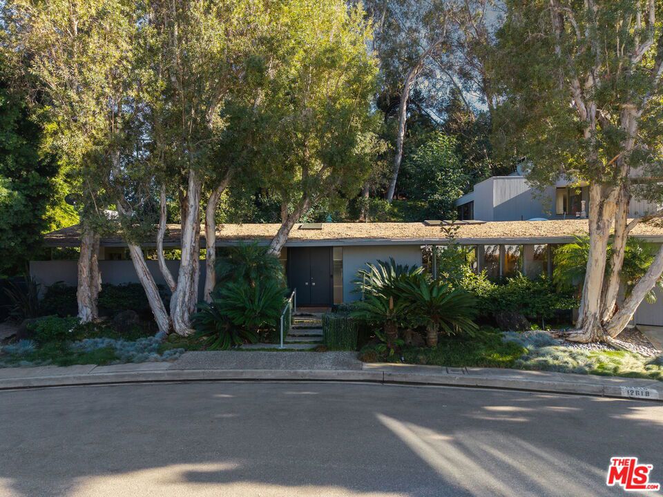 This stunning architectural residence by architects Benton and Park blends modern design with timeless elegance in the heart of Brentwood. Offering 4 bedrooms and 4 bathrooms, this home is filled with natural light and verdant green backyard views from floor-to-ceiling windows and skylights, creating seamless indoor-outdoor living. The upstairs private primary suite is a true retreat, complete with a sun deck, two large walk-in closets, and a spa-like bathroom. Designed for both work and leisure, the home includes two private offices, a family room with wet bar, a striking solarium, and conditioned wine storage. The chef's kitchen features professional-grade stainless appliances, an eat-in dining area, and an effortless flow to the center hall and living spaces. A dedicated laundry room and two-car garage add everyday convenience. Step outside to a lushly landscaped backyard oasis with a pool, waterfall, and hot tub, perfect for relaxation and entertaining. Central heating and air conditioning ensure year-round comfort. This is more than a home it's a rare architectural jewel offering style, comfort, and timeless sophistication in one of Los Angeles' most coveted neighborhoods, in a rare and quiet cul-de-sac location.