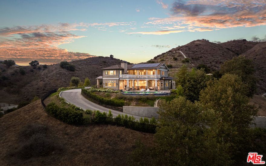 Featuring 26767 Mulholland Highway, this offering is more than just a residence, it's a showcase of privacy, design, and the quintessential California lifestyle. Tucked behind a gated, private drive and embraced by rolling hills, this custom-built contemporary craftsman estate offers approximately 7,269 square feet of refined living, perfectly balancing sophistication and comfort. With five bedrooms, seven bathrooms, and sweeping canyon vistas from nearly every angle, the home lives like a secluded resort, set in the heart of Calabasas, yet only fifteen minutes from Malibu's shoreline. The arrival makes an impression with a spacious motor court, natural landscaping, and unobstructed views of the Santa Monica Mountains. Inside, every detail has been thoughtfully curated. Wide-plank oak flooring, hand-selected stone, Italian light fixtures, and a top-tier Gaggenau appliance collection create an atmosphere of understated luxury. The open layout flows effortlessly through formal and casual living and dining spaces, a chic full-service bar, and an entertainer's kitchen featuring a large island, cozy breakfast nook, and seamless connection to the gathering areas. The large primary suite crowns the upper level as a retreat of light and tranquility. Walls of glass frame hillside views, while the spa-like bath is complete with dual vanities, a soaking tub, and an oversized marble shower with dual rain heads. A generous walk-in closet space awaits customization. Upstairs also features three additional en-suite bedrooms and a media lounge that extends to a terrace with a fireplace, ideal for savoring Malibu sunsets with a glass of wine. Outdoor living defines the estate, featuring an infinity-edge pool and spa that merge with the horizon, while multiple patios, a fire pit lounge, a full outdoor kitchen, and a flat grassy yard invite year-round gatherings. With no neighbors in sight, the setting ensures total seclusion beneath starlit skies. Blending intentional architecture with timeless design, this residence offers a rare opportunity close to the Commons and the Malibu Coast, yet worlds apart in atmosphere. Crafted for those who value lifestyle, leisure, and elegance, it's a home designed to endure as a legacy.