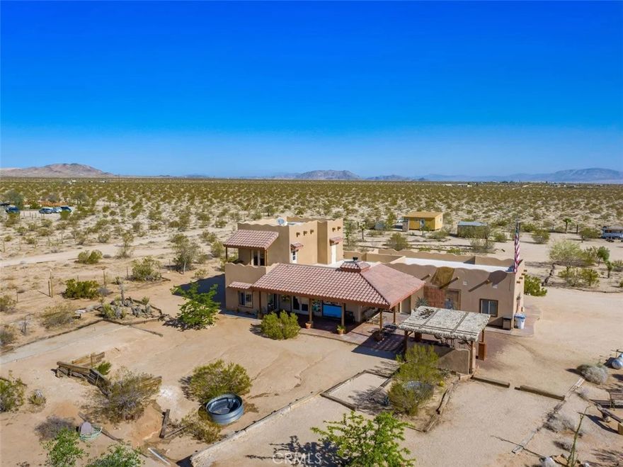 Tranquility & privacy awaits! This newly upgraded three bedroom, three bath home is located on 15 acres right in the heart of Joshua Tree. Throughout the home you’ll enjoy the simple yet thoughtful touches that slowly transform your busy thoughts into a relaxed, meditative state. Conveniently located 20 minutes from Joshua Tree National Park, 13 miles from black rock nature center & 8 miles from local grocery stores. Unobstructed poolside views of Joshua Tree National Park perched on the southern horizon. Newly constructed Pebble Tec pool blends seamlessly with the landscape. This 15-acre ranch, located 20 minutes from Joshua Tree National Park and 13 miles from Black Rock Nature Center, perfectly merges luxury with the raw essence of the desert. Relax in the 50-foot pool or enjoy a tranquil evening in the 10-person spa. Pride of place is the outdoor patio, adorned with awe-inspiring artwork crafted by Master Artist Troy Bryant and 100 other local talents, ingeniously piecing together portraits of the very animals who once roamed this ranch. This outdoor space also features a barbecue area complete with ample seating, ideal for those who love to host. Nestled in its harmonious environment, you won't find a neighbor for at least 3/4 of a mile in any direction. Bask in the serene privacy of this secluded gem where you can lay under the stars unclothed if you so choose, with not a soul in sight. This desert gem sleeps 13, offers a 3 bedroom, 3 bath cheerful, sun-bathed living space fully furnished with a 3-car garage and includes multiple outdoor sheds and 2 Conex boxes for all of your storage needs. 20kWh of solar and 2 Tesla batteries provide peace of mind by eliminating the electric bill and giving seamless protection in the event of any power outages. There are 2 industrial swamp coolers designed to cool the house and mini splits in each room to bring each area to your desired comfort level. The roof deck allows for nearly 360° views of Joshua Tree taking sunrises and sunsets to a whole new level. The 5-acre lot that adjoins the house lot has a little dirt racetrack for UTVs, dirt bikes, or ATVs, and even a 5-acre lot to the south with a paid water meter on it. The grounds are intricately lined with railroad ties from the very tracks that helped pave the West. The existing infrastructure, including water spigots at each animal pen and intact fencing, allows the new owner to easily revive the bustling ranching operation if desired.