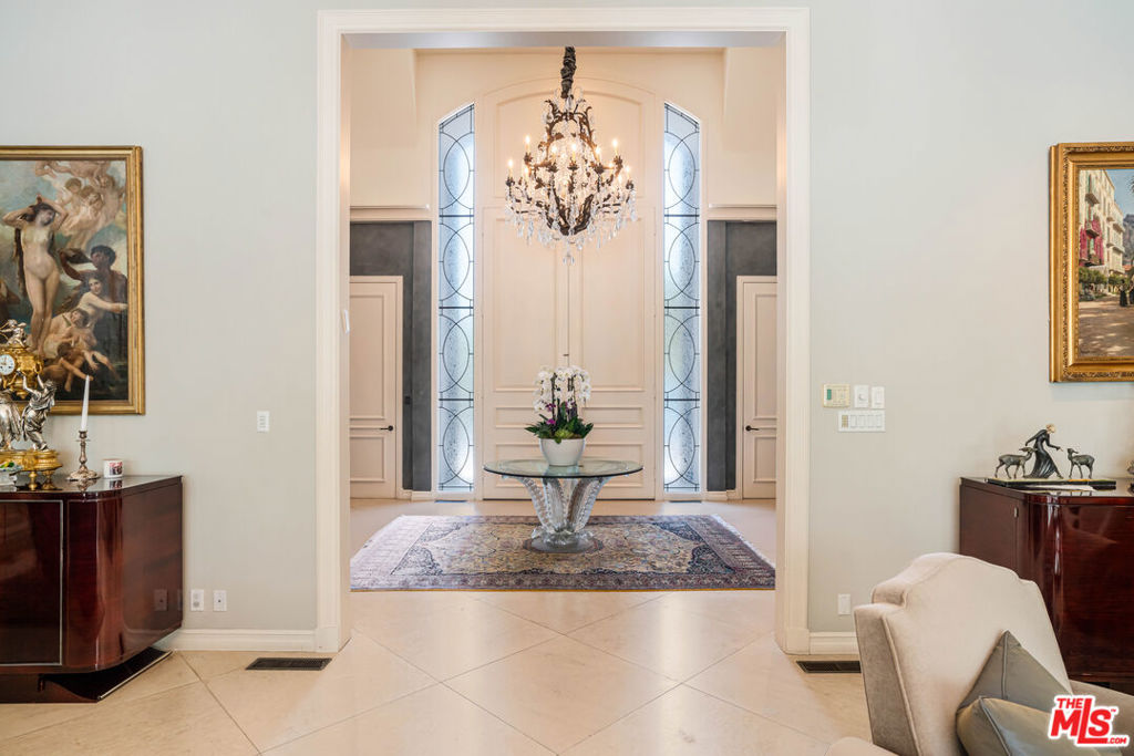 Introducing 915 Hartford Way, a timeless French Regency estate nestled behind private gates in prime Beverly Hills, just moments from the iconic Beverly Hills Hotel. This architectural gem blends elegance, sophistication, and serenity across beautifully landscaped grounds. Step through grand double doors into a dramatic two-story foyer. The formal living room showcases a stately fireplace and walls of glass framing lush surroundings. An open floor plan connects refined living spaces, including a formal dining room with soaring ceilings and tranquil views, and a charming breakfast room with direct outdoor access. The gourmet kitchen is a chef's dream, featuring a central island, top-tier appliances, and seamless design. A cozy family room/den boasts rich wood floors, custom built-ins, a fireplace, and an adjoining office. The luxurious primary suite offers a peaceful retreat with fireplace, dual walk-in closets, and a spa-like bath with soaking tub and walk-in shower. Two additional guest suites on the main level feature custom finishes and garden views. Upstairs, find a spacious guest room with its own bath and an expansive bonus room ideal for entertainment or play. Outdoors, enjoy a resort-style oasis with lush gardens, a covered terrace, pool, fire pit, bar, and multiple dining areas and lounge spaces. Additional amenities include maid's quarters, a wine cellar, and a 3-car garage. A rare offering of privacy, luxury, and proximity to world-class shopping, dining, and entertainment. Shown to prequalified buyers only.