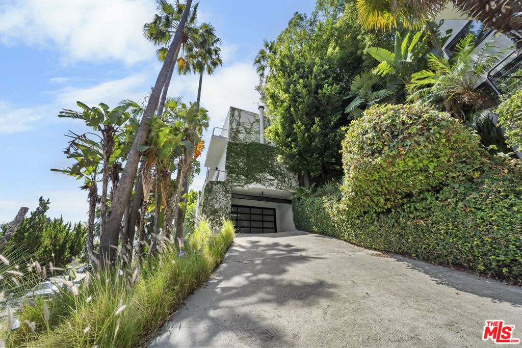 Renovated and thoughtfully reimagined for modern living, this striking Steven Hill-designed architectural home is a standout in one of Los Angeles' most sought-after neighborhoods. Showcasing high-volume ceilings and expansive open spaces, the residence is anchored by a harmonious blend of natural materials - wood, glass, and stone - that create warmth and sophistication throughout. The chef's kitchen, complete with bar seating, seamlessly flows into a spacious dining area ideal for holiday gatherings and entertaining. Upstairs, the primary suite is a luxurious retreat featuring an oversized walk-in closet, cozy sitting area, and a spa-inspired bath with a soaking tub and dual shower. Adjacent to the primary are a guest bedroom and a versatile office with its own walk-in closet, easily convertible back into a third bedroom if desired. A unique outdoor catwalk from the primary suite leads to lush, terraced gardens and private patios, offering panoramic views and tranquil outdoor living. Every detail has been considered, with premium amenities including a security system, built-in sound and intercom systems, tankless water heater, newer Fleetwood doors, Lutron smart lighting, and a two-car garage. This is a rare opportunity to own a truly special modern residence that effortlessly combines thoughtful design with luxurious comfort!