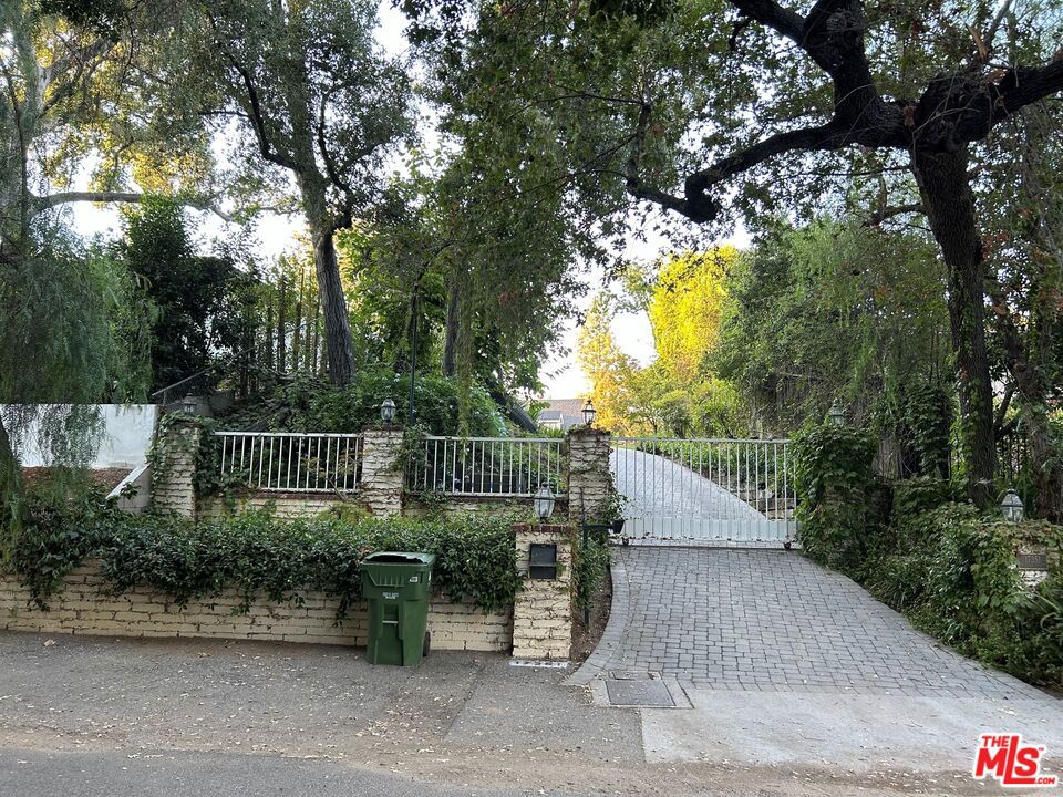 Great Celebrity Compound! Welcome to this elegant 8,521 square foot estate, nestled on a sprawling 35,309-square foot private gated flag lot in the prestigious Rancho Estates area of Encino. This private and stunning home features six bedrooms and six bathrooms (four full and two half) in the main house, providing ample space for family and guests. The primary bedroom is a true retreat, complete with two spacious closets, large primary bathroom with a shower and soaking tub. Enjoy multiple living spaces, including a formal living room, dining room, bar, family room, office/media room, breakfast area, and playroom, all designed with comfort and style in mind. Additionally, the property includes a guest house with its own office, bedroom, and bathroom...ideal for visitors or a private workspace or home office. The charm of this home extends to its exterior, boasting a picturesque wrap-around porch and beautiful grounds. The huge yard is perfect for outdoor activities and entertaining, featuring a sparkling pool and spa. There's even an adorable structure that is perfect for a she-shed or to tinker as you see fit. Architectural details such as multiple gables, a pitched roof, stone accents, and an oversized fireplace add to the original 1924 charm of this traditional home. The original home was extensively expanded and updated in 2009, and maintains its original charm. The pool and spa offers a serene spot to relax and enjoy the extremely private surroundings. There is a large motor court for many cars as well as a carport for three vehicles. This property seamlessly blends luxury and comfort, making it an ideal home and an entertainer's dream. Don't miss the opportunity to own this exquisite estate. The home is being prepped for sale, but the seller would be willing to entertain offers prior to painting, some touch-ups, and staging. (7391 sq ft for main house, 1130 sq ft for guest house=8521 total)