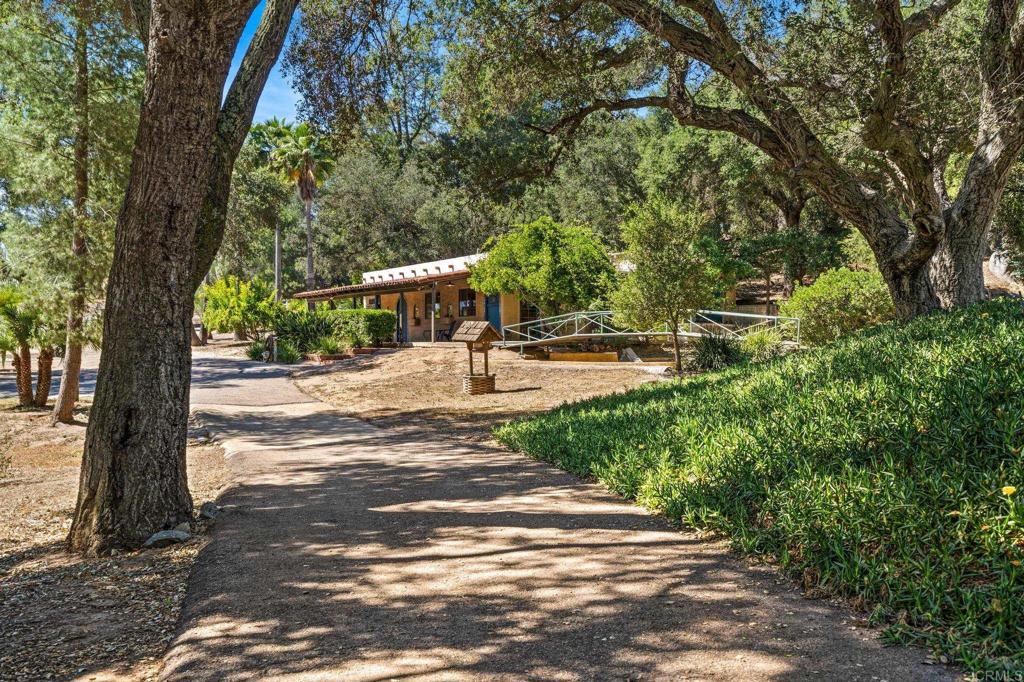 Escape to your own private sanctuary in the heart of Valley Center, a peaceful rural community situated in North San Diego County known for its rich agricultural heritage, wide-open spaces, and relaxed country lifestyle. Here, on 24± usable acres of gently rolling terrain, you'll find a rare blend of natural beauty, privacy, and agricultural opportunity. Tucked away in a quiet, secluded setting, this exceptional ranch features a healthy oak grove that creates a lush, park-like atmosphere, while a seasonal stream meanders through the landscape, enhancing the serenity and charm of the land. Valley Center’s temperate climate and fertile soils make it ideal for a variety of agricultural endeavors, and this property is perfectly suited for horses, orchards, livestock, or hobby farming. A charming, character-rich 3 bedroom, 2.5 bath hacienda-style home features classic decorative tile, arched accents, an open-concept main living space perfect for entertaining. Each bedroom includes its own cozy fireplace, while expansive front and side verandas invite seamless indoor-outdoor living. Adding to its appeal, a second home on-site presents a valuable opportunity for rental income, guest accommodations, or housing for a ranch manager. Whether you're seeking a productive working ranch, a multi-generational estate, or a peaceful country escape, this enchanting property embodies the best of Valley Center's rural charm and agrarian lifestyle. Fully fenced and cross-fenced, the land offers functional versatility, while both municipal water and a private well provide reliable and abundant water access for residential use and agricultural needs. This vintage estate offers more than just a beautiful home—it’s a wonderland for families. With shady woods, a babbling creek, and built-in fun like tree swings and climbing areas, it’s the perfect place for kids (and kids-at-heart) to explore, imagine, and play. A magical blend of timeless character and outdoor adventure awaits. 13511 Hilldale Road, Valley Center, CA 92082