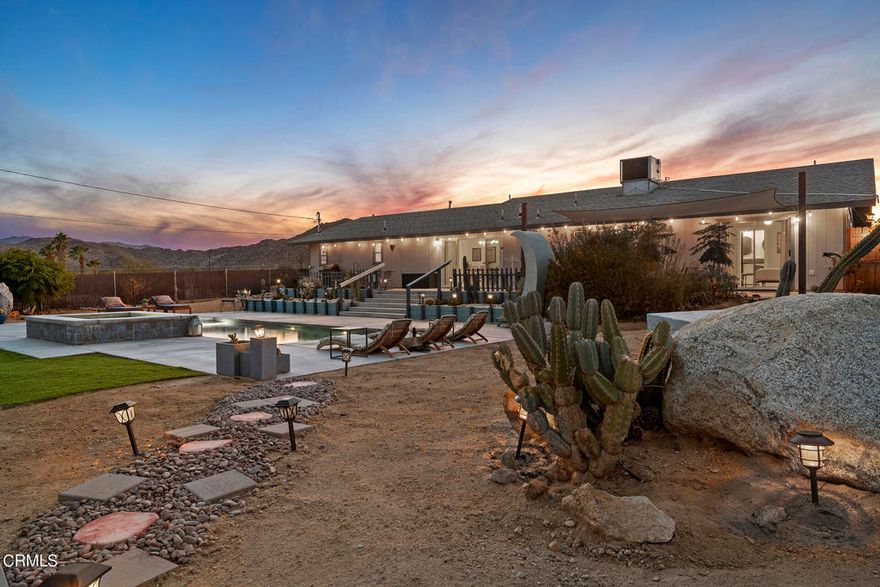 Escape to your own desert oasis in this beautifully remodeled Joshua Tree retreat, where modern comfort meets serene high-desert living. Completely updated in 2019, this turnkey home features paid-off solar and a resort-style saltwater pool and spa. The inviting great room includes a stylish kitchen with stainless steel appliances, a cozy living area with an electric fireplace, and a breakfast nook perfect for morning coffee. The home includes four spacious bedrooms and three bathrooms, with two bedrooms featuring en-suite baths and pool views. A third bath, office, and attached garage converted into a game room add flexibility. Large sliding doors open to a stunning backyard surrounded by lush desert landscaping, with multiple outdoor zones for relaxing or entertaining--enjoy shade sails, a hammock, fire pit, BBQ area, and endless stargazing under the desert sky. Set on nearly half an acre in a peaceful neighborhood, this home offers privacy and tranquility just five minutes from downtown Joshua Tree and fifteen minutes from the National Park entrance. Offered fully furnished, move-in ready, and near local favorites like Crossroads, the Dez & the weekly farmer's market, this incredible property embodies the essence of desert living.