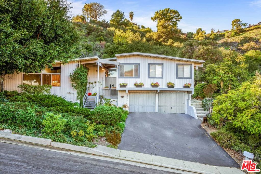 Spacious mid-century split-level on a rare scenic acre. Double-door entry opens to an airy atrium and step-down living room with fireplace, pitched beam ceilings, and walls of glass overlooking the patio and expansive backyard. Elevated dining room with built-in buffet and hardwood floors. Center-island kitchen/family room with breakfast bar, gas appliances, and sliding doors to an oversized covered patio ideal for entertaining. Three bedrooms on the main level share a large bath with dual sinks; private upstairs primary suite features canyon views, wall of closets, and spa bath with soaking tub and separate shower. Wood/tile floors, skylights, abundant windows, 2-car garage, and seamless indoor-outdoor flow. The expansive backyard is an entertainer's dream, offering ample space for gatherings and relaxation. Property is not currently staged.