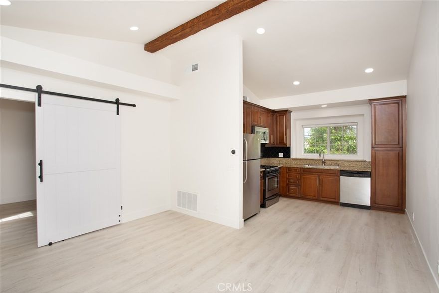 Comfort, style, and convenience unite to create the perfect sanctuary, this delightful carriage unit condo in the desirable, gated community of Canyon Villas. Ascend one flight of stairs where  a private and serene patio welcomes you. Once inside, enjoy an open floorplan bathed in natural light, creating an inviting and refreshing ambiance. Adjacent to the living room, the updated kitchen features stainless steel appliances, granite countertops, and a farmhouse sink. Tucked  behind a stylish barn door, is  the spacious  bedroom featuring an ensuite bathroom and walk-in closet, providing ample storage space. Recently remodeled with attention to detail, this unit boasts tasteful vinyl flooring throughout, recessed lighting, updated hardware, and doors. Additional features include beamed ceilings, A/C, a 1-car garage with storage space (no direct access), and a private laundry room complete with a full-size washer and dryer, conveniently located off the patio. Indulge in the luxury of Canyon Villas' exceptional amenities, which include two pools, spas, fitness center, and clubhouse for social gatherings. The 73 freeway, parks, scenic trails, and Aliso Viejo Town Center with shopping, dining, and a movie theater is just moments away.