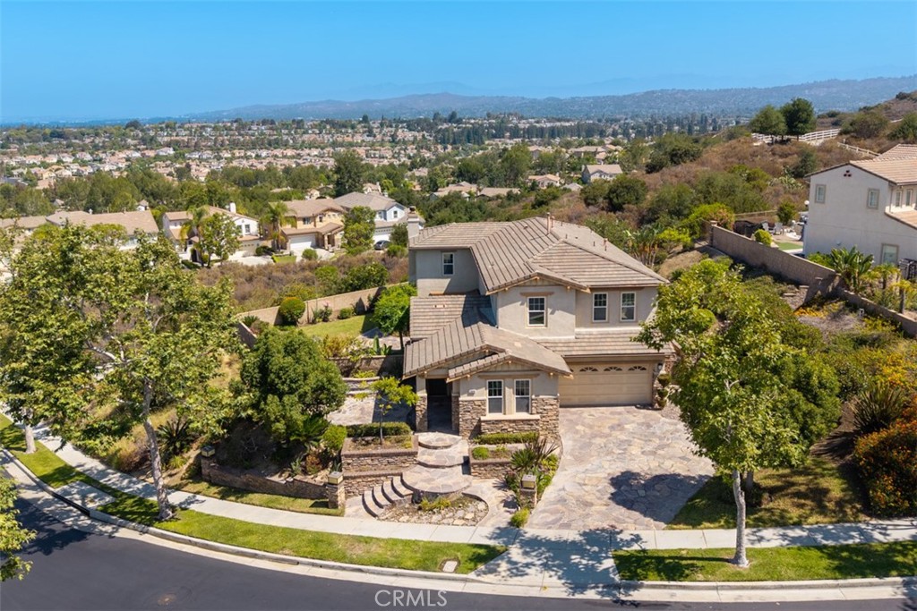 Perched at the end of a tranquil tract, this property awaits its future owner longing to behold privacy and sweeping views of both nature and the city skyline. Situated on a desirable rectangular lot, the property boasts a generous yard perfect for outdoor entertaining or simply soaking in the serene surroundings. Earth-toned stacked stone detailing complements the stucco exterior, enhancing the facade aesthetic with natural depth and character. Step inside to discover well-appointed spaces with soaring ceilings beautifully finished with crown molding. The formal living room that looks out to garden views through full sized windows allows natural light to permeate the space. Directly across is a main floor ensuite bedroom presently dressed as a home office with a custom work desk and shelves. The open hallway lead you to the dining room anchored by a chandelier setting the mood for formal meals. The open-concept kitchen and family room create the perfect stage for everyday living and effortless entertaining. The remodeled kitchen features granite countertops, extended workspaces and abundant cabinetry keeping everything within reach but out of sight. Upstairs, the expansive primary suite is a true retreat, featuring a luxuriously spaced bedroom and bathroom enhanced with dual vanities, his-and-hers walk-in closets, a soaking tub, a separate walk-in shower and a private toilet. Additional 3 bedrooms are generously sized, offering comfort and privacy for all. Discover a private outdoor sanctuary with boundless potential to transform into a resort-style retreat. Set on an expansive, rectangular lot, this yard offers the perfect canvas to create your dream outdoor oasis. Imagine multiple serene water features weaving through the landscape, a custom fire pit for cozy evenings under the stars, and an elegant water fountain providing a tranquil backdrop of gentle sound and movement. Entertain in style with the future addition of a fully equipped outdoor barbecue kitchen, ideal for al fresco dining and weekend gatherings. The tiered side yard presents an incredible opportunity to create your own fruit-bearing garden. With ample room to expand and personalize, this indoor-outdoor space offers the rare combination of privacy, security & versatility, ready to be transformed into a one-of-a-kind forever home. Whether you're dreaming of a home on a grand scale or a simple haven that exudes Peace and Gratitude, the possibilities here are as expansive as the views.