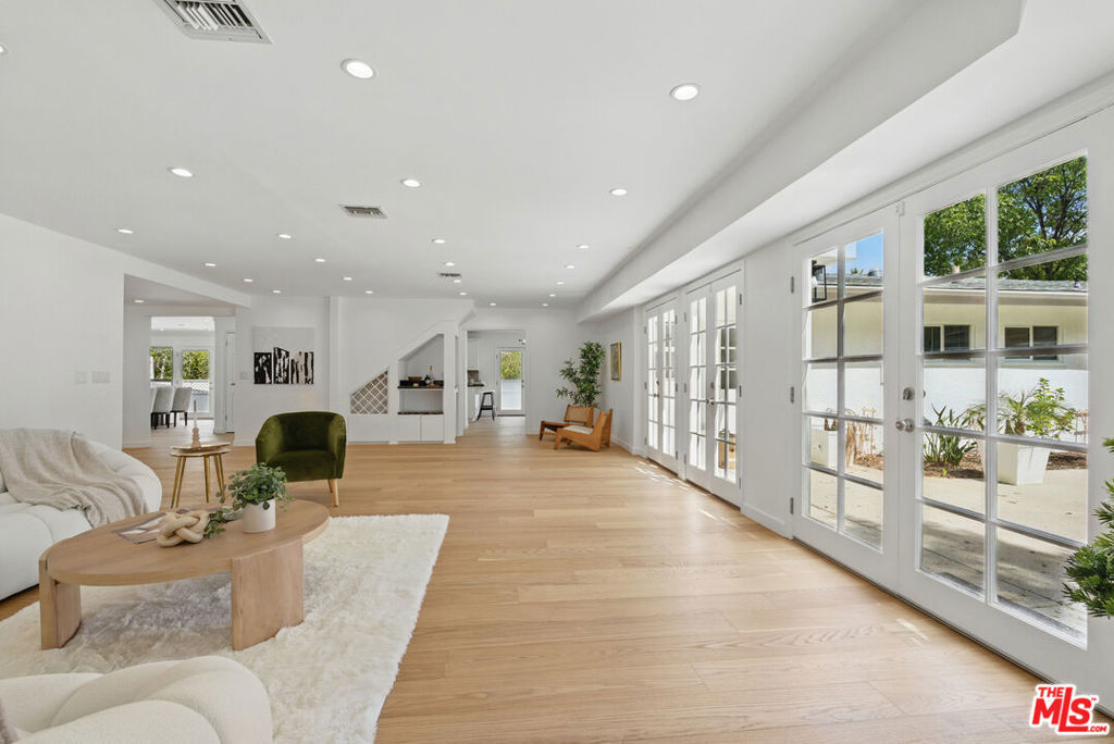 This enchanting storybook home, nestled on a peaceful, tree-lined street, seamlessly blends modern updates with timeless charm. Set on nearly 20,000 sqft, the property offers exceptional curb appeal with five spacious bedrooms, four bathrooms, a half-circle driveway, and mature landscaping, creating a private paradise. Inside, the contemporary traditional design radiates natural warmth, featuring custom White Oak flooring, recessed lighting, a cozy fireplace, and a stylish bar area bathed in abundant natural light. The expansive dining room, with an additional nook and grand fireplace, is perfect for entertaining. The chef's kitchen offers generous cabinetry, countertop space, a breakfast area, breakfast bar, and high-end stainless steel appliances. The primary retreat is a true sanctuary with vaulted ceilings, a private balcony, a spacious walk-in closet with custom cabinetry, and an en suite bathroom with a rainfall shower, Jacuzzi tub, skylight, and double vanity. The backyard is an oasis, with an oversized pool, waterfall Jacuzzi, charming cabana, and an outdoor kitchen with a grill and sink ideal for al fresco dining and entertaining. The expansive lawn provides endless possibilities for recreation and space. Additional features corner lot including a side driveway leading to the bottom level, an attached two-car garage, an expansive side yard, a dedicated laundry room, and central AC/heat. Conveniently located near trendy restaurants, shopping, and amenities such as The Village, Cedars-Sinai, Whole Foods, and Equinox, with easy access to the 101 Freeway, this home offers the perfect balance of privacy, luxury, and convenience. Prepare to be amazed.
