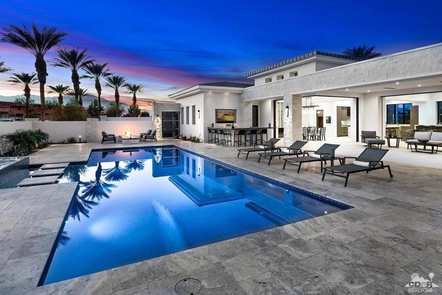 Located on one of the largest custom lots in desirable Toscana Country Club, this light-filled desert-modern home captures mountain and sunset views across the private south-facing front courtyard. Experience truly open indoor/outdoor living, dining and entertaining with five walls of disappearing glass opening seamlessly to a generous outdoor living room and patio surrounding the pool with cascading spa. Outdoor shower and pergola above outdoor bar/kitchen and putting green recently added. Adjacent, the great room with grand fireplace and walk-behind wet bar, the state-of-the-art kitchen with huge island and butler's pantry will please the most discriminating chef and caterer alike. Formal dining room with full glass wall wine room. The luxurious master suite with fireplace includes two equally generous closets, large walk-in shower, dual vanities and water closets, and a private retreat to use as an office, sitting area or exercise room. The junior master suite with golf course view and a separate entrance guest house with its own living room, kitchenette and 2 en suite bedrooms, are sure to please family and friends. State of the art AV system, disappearing movie screen, high efficiency HVAC and so much more.  Offered furnished per Inventory including 2 golf carts.